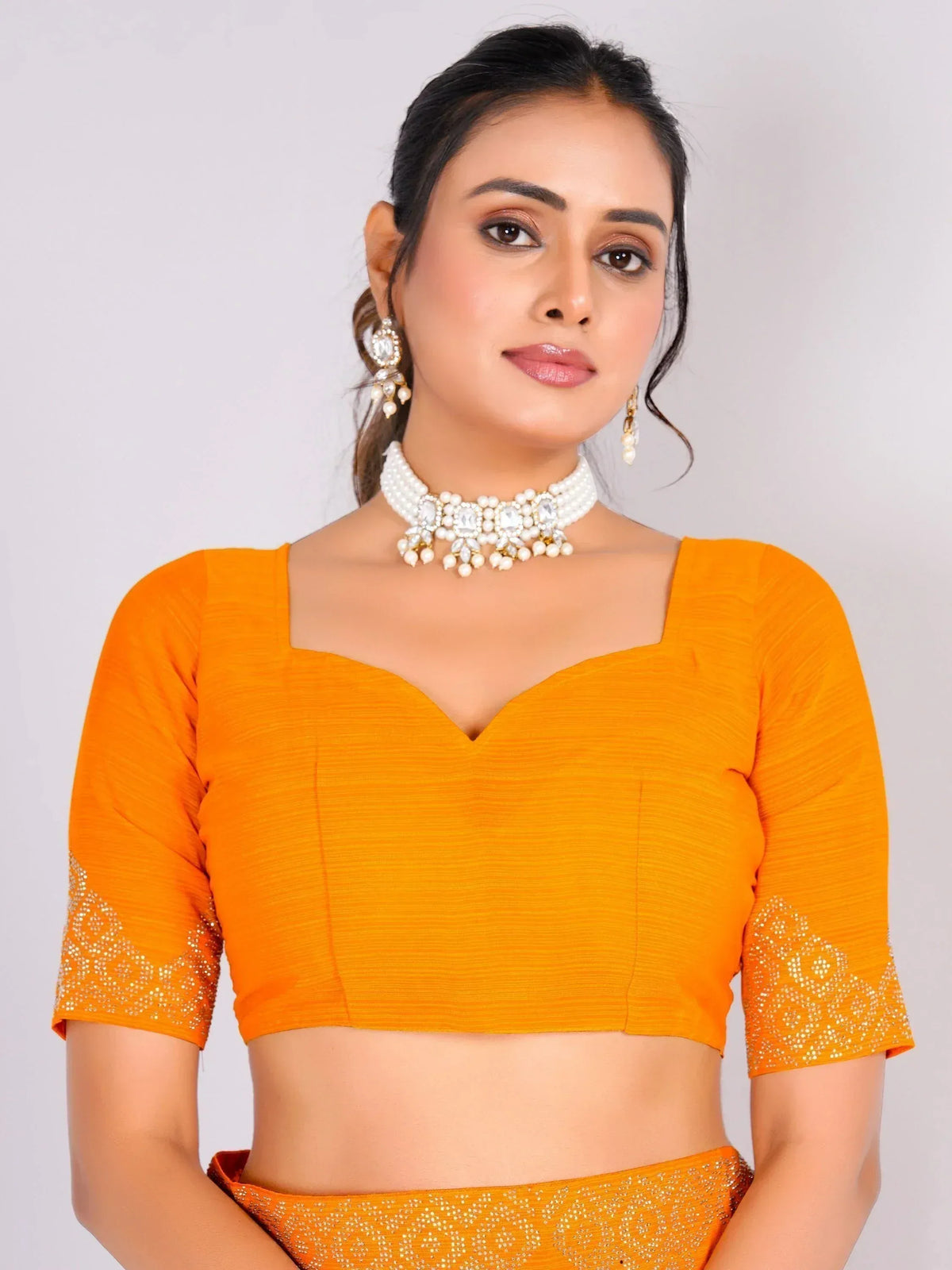 Orange ethnic blouse with embellished sleeves, paired with pearl choker and earrings for festive wear