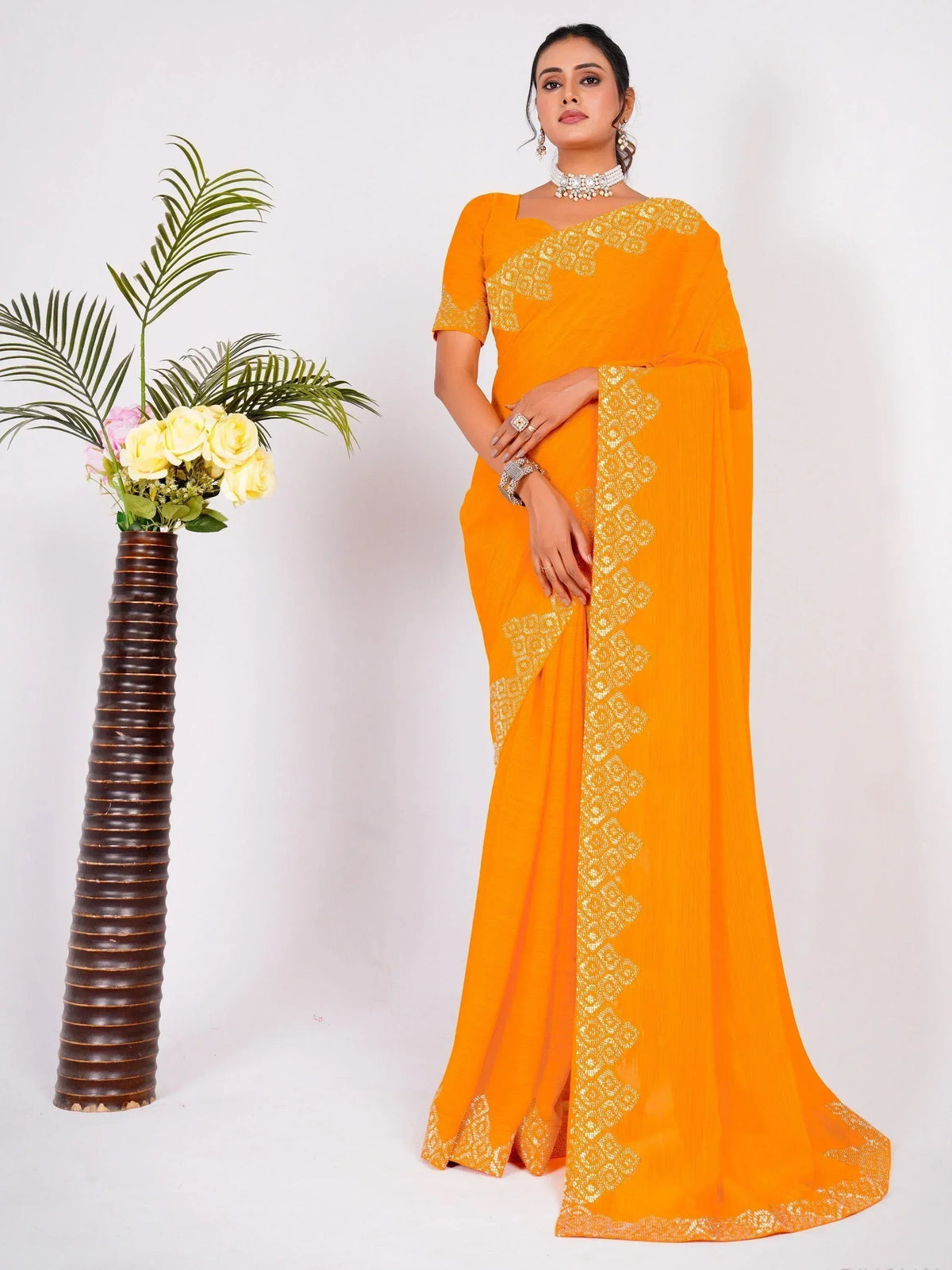 Vibrant orange saree with gold embroidery, styled with traditional jewelry for ethnic occasions