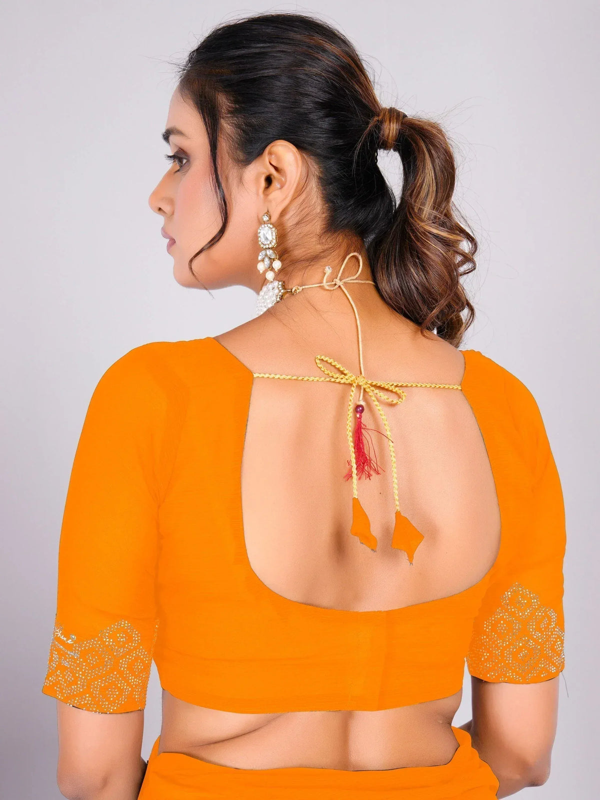 Orange ethnic blouse with open back, tie-up detail, and sleeve embroidery for saree or lehenga