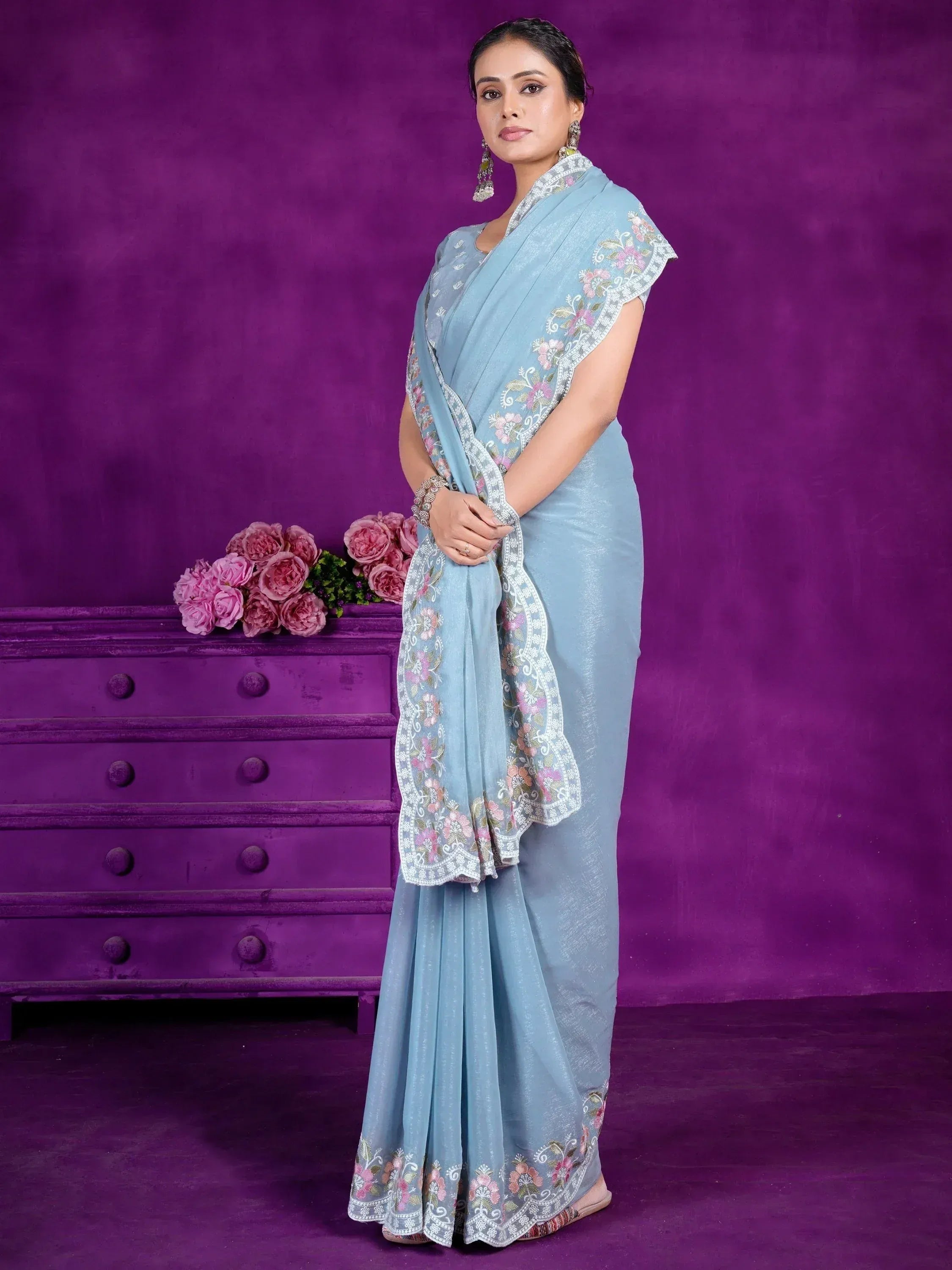 Light blue embroidered saree with floral border, styled with matching blouse and statement earrings