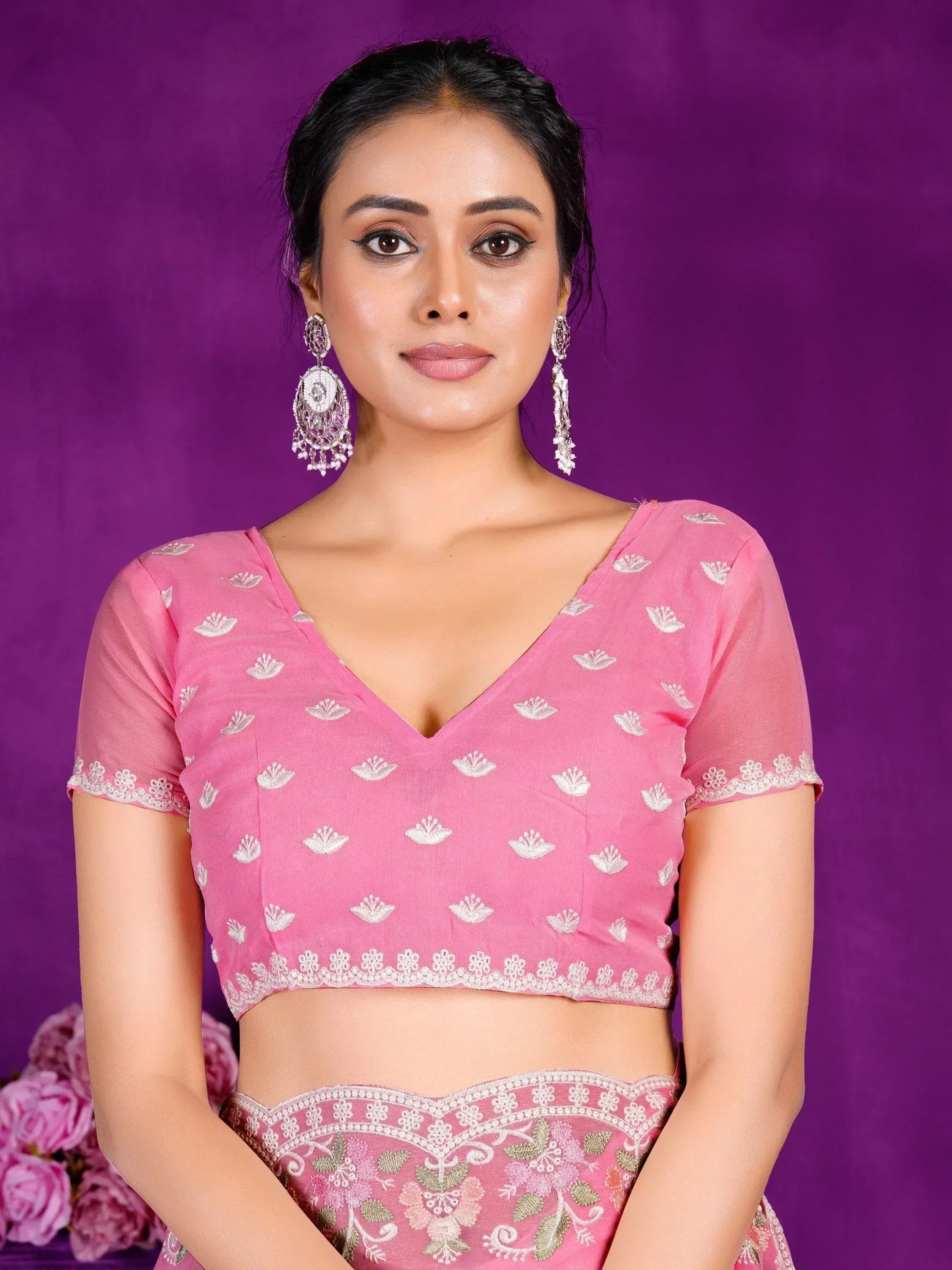 Pink embroidered lehenga choli with floral motifs and lace trim, paired with statement earrings