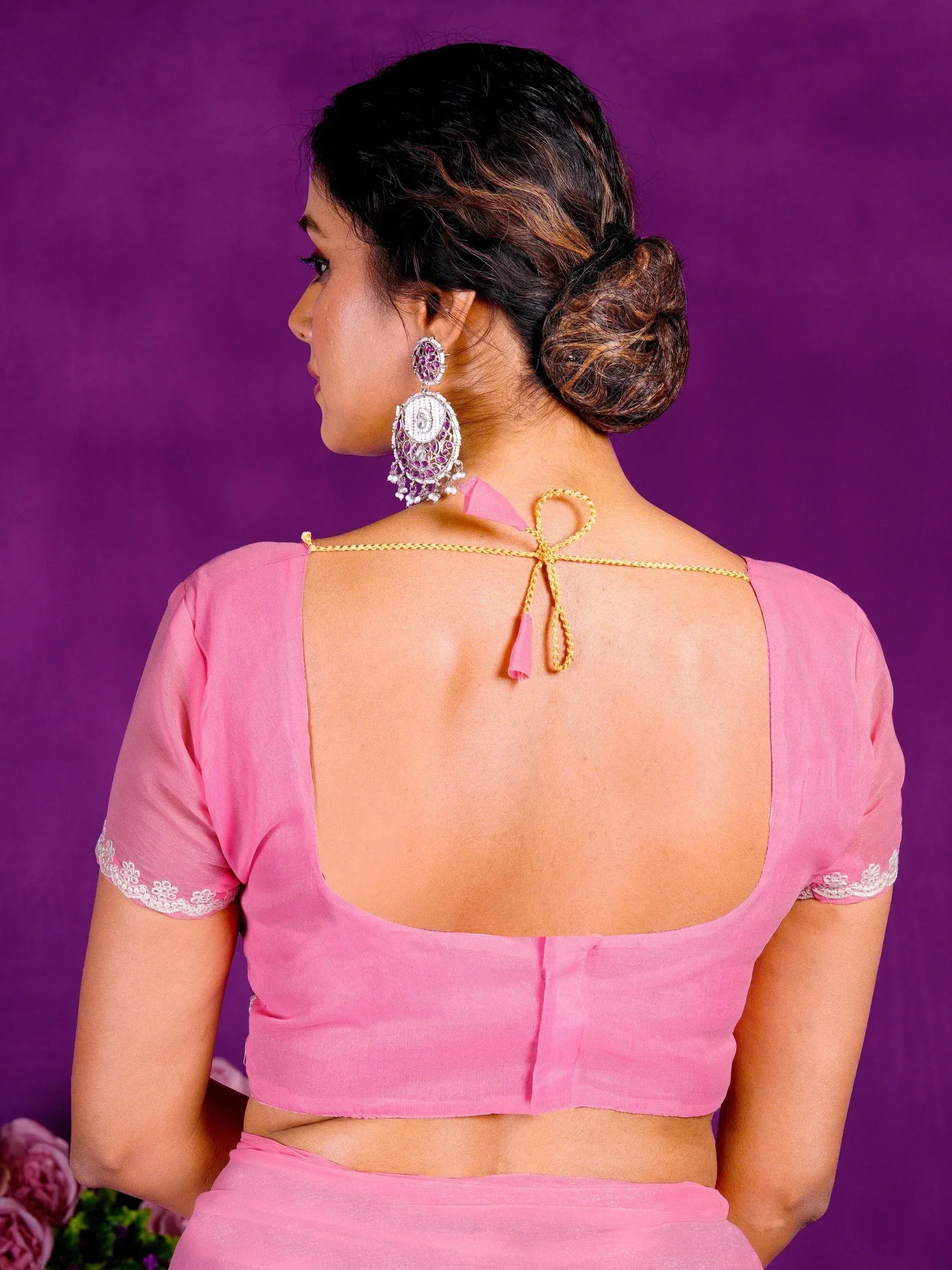 Pink backless blouse with lace sleeves and gold tie, paired with statement earrings for ethnic wear