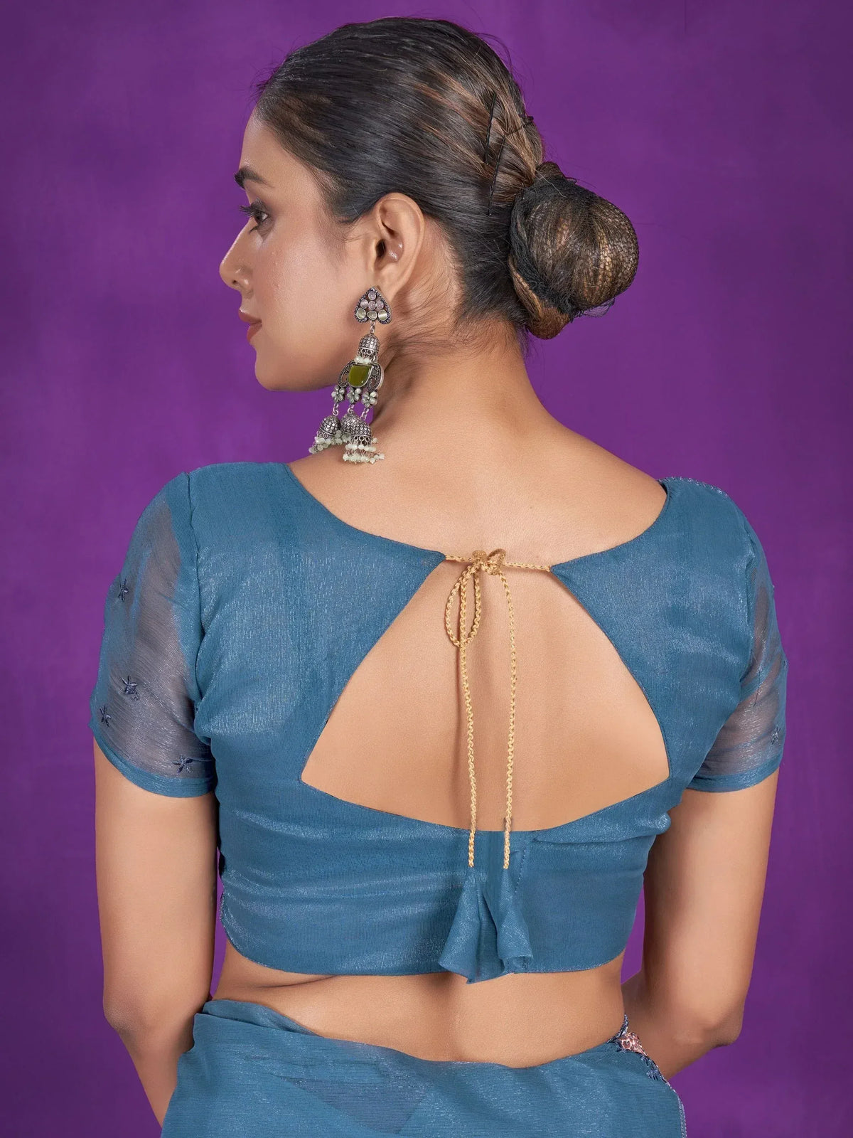 Blue saree blouse with back cutout and gold tie, paired with ethnic jhumka earrings