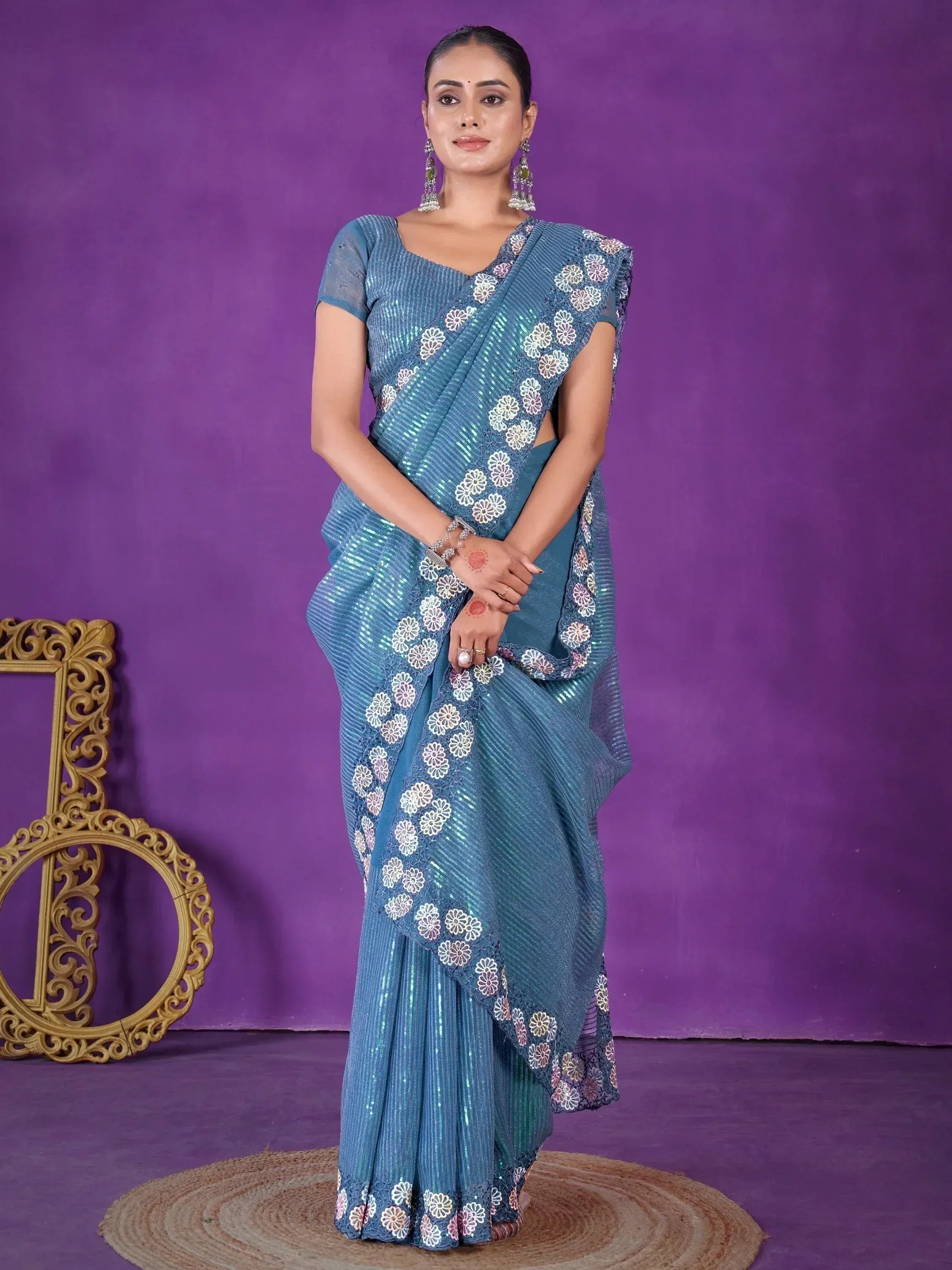 Blue sequin saree with floral embroidery, styled with matching blouse and jhumka earrings for ethnic occasions