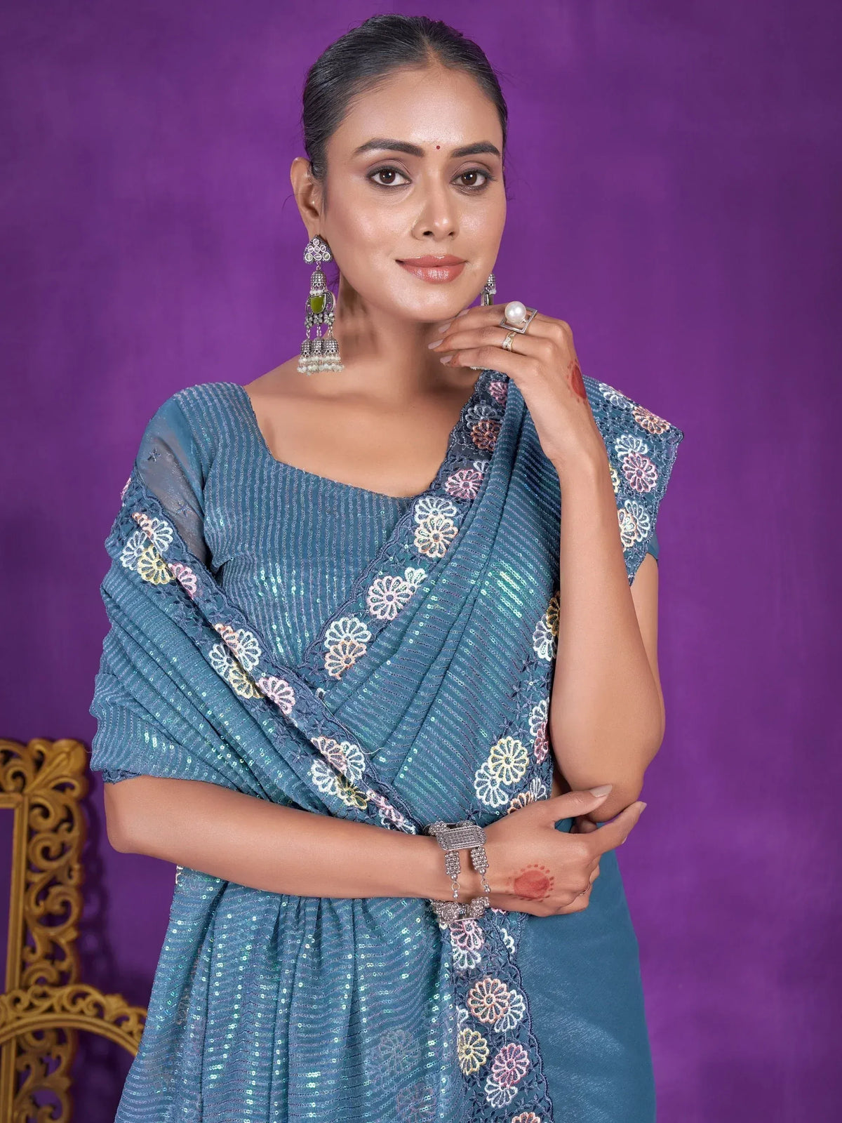 Woman in teal sequin saree with floral embroidery, traditional Indian ethnic wear, paired with jhumka earrings