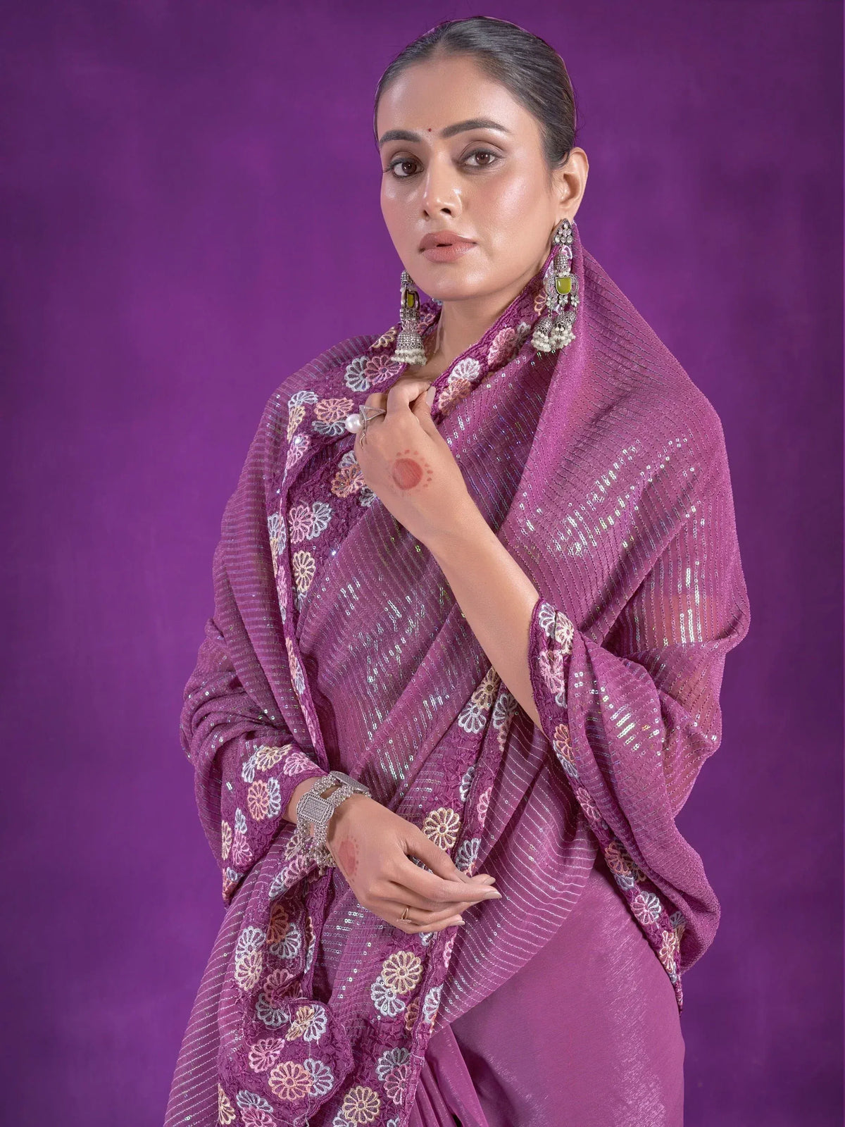 Purple ethnic saree with floral embroidery and sequin detailing, styled with traditional jewelry for festive occasions