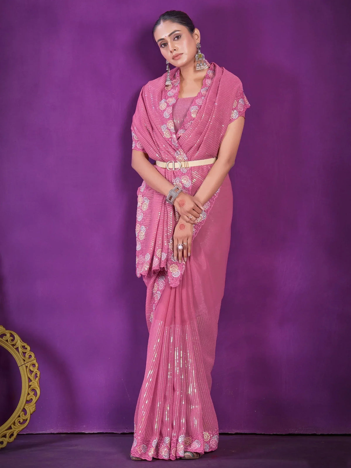 Pink sequin saree with floral embroidery, styled with belt and statement earrings for ethnic occasions