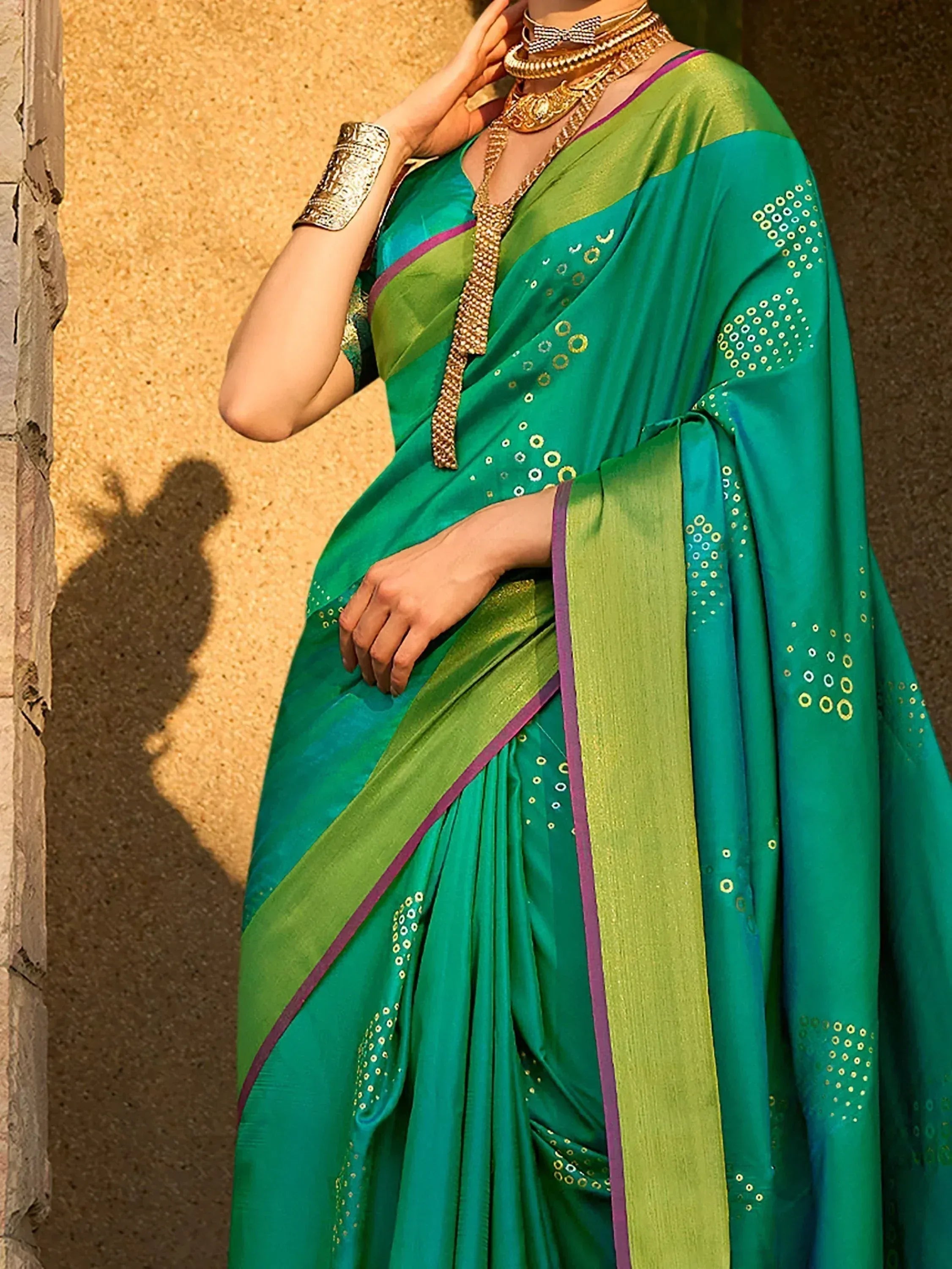 Emerald green saree with gold embroidery and purple border, styled with traditional Indian jewelry