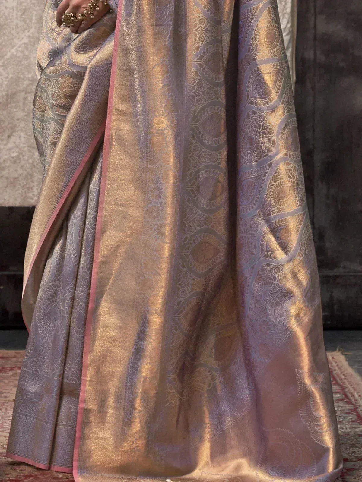 Elegant lavender and gold designer saree with intricate paisley weave and pink border, perfect for Indian ethnic occasions.