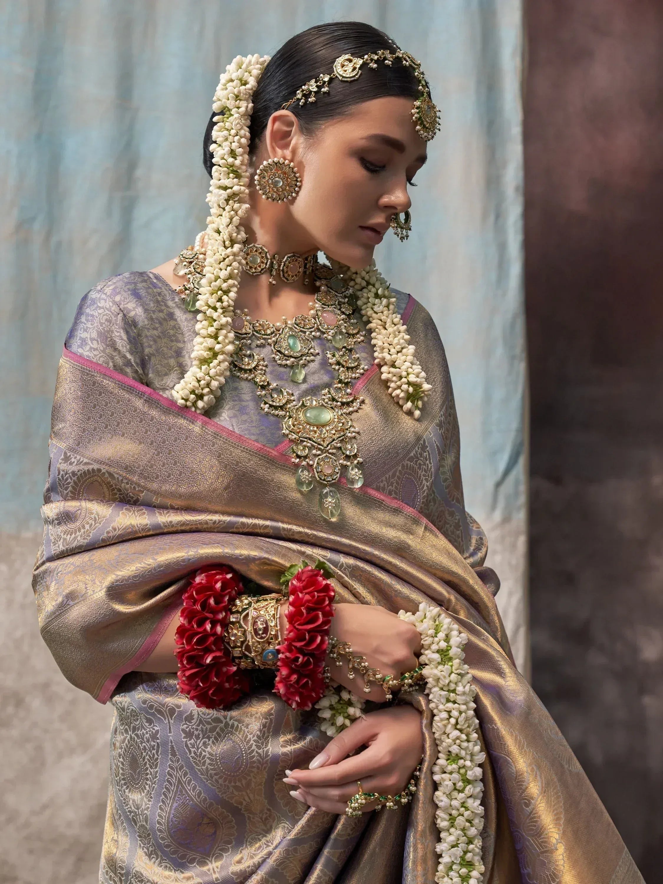 Woman in elegant Indian saree with gold jewelry and floral garlands, perfect for weddings and festivals.