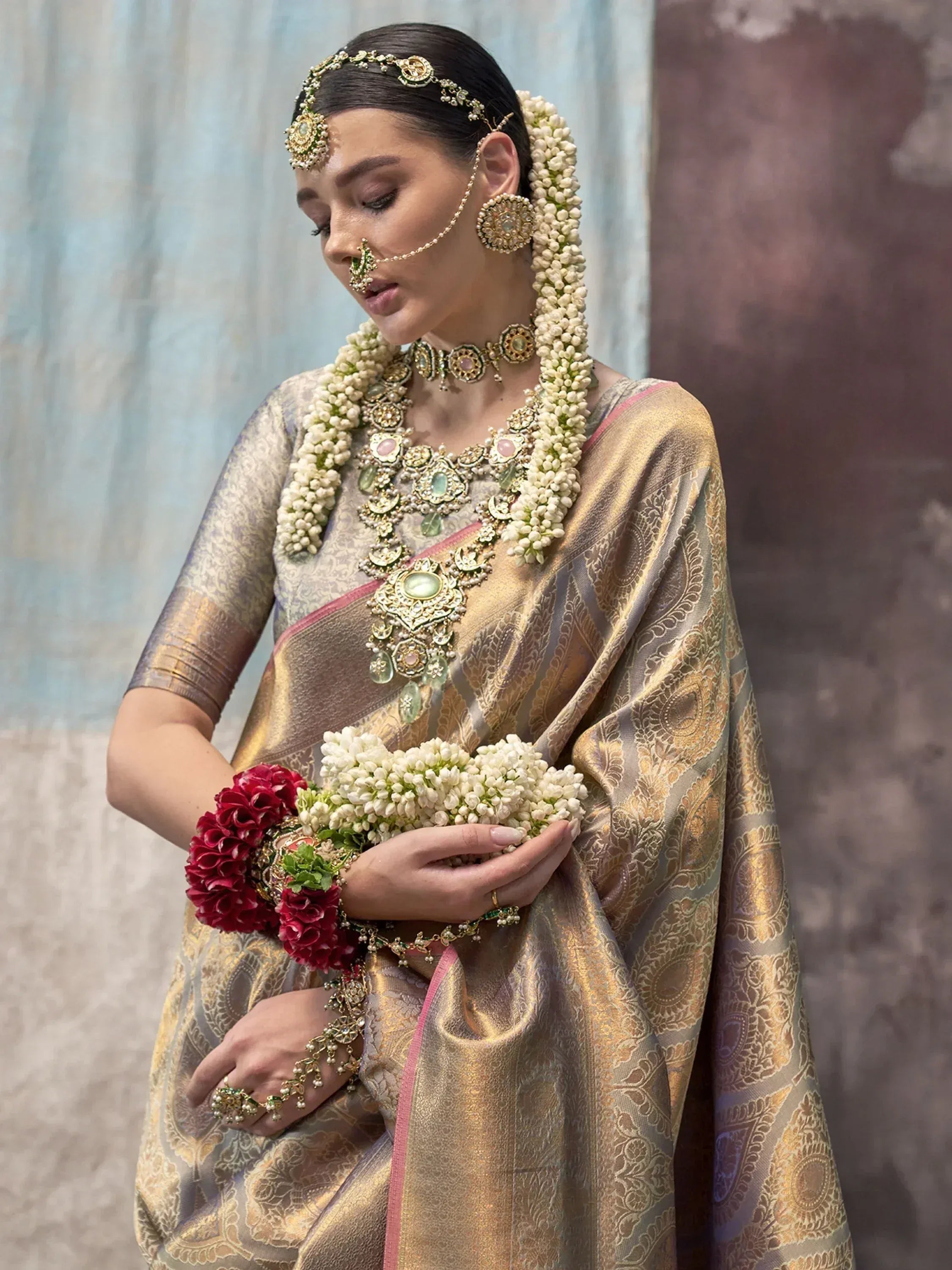 Woman in golden ethnic saree with floral jewelry and jasmine garlands, perfect for Indian weddings or festivals.
