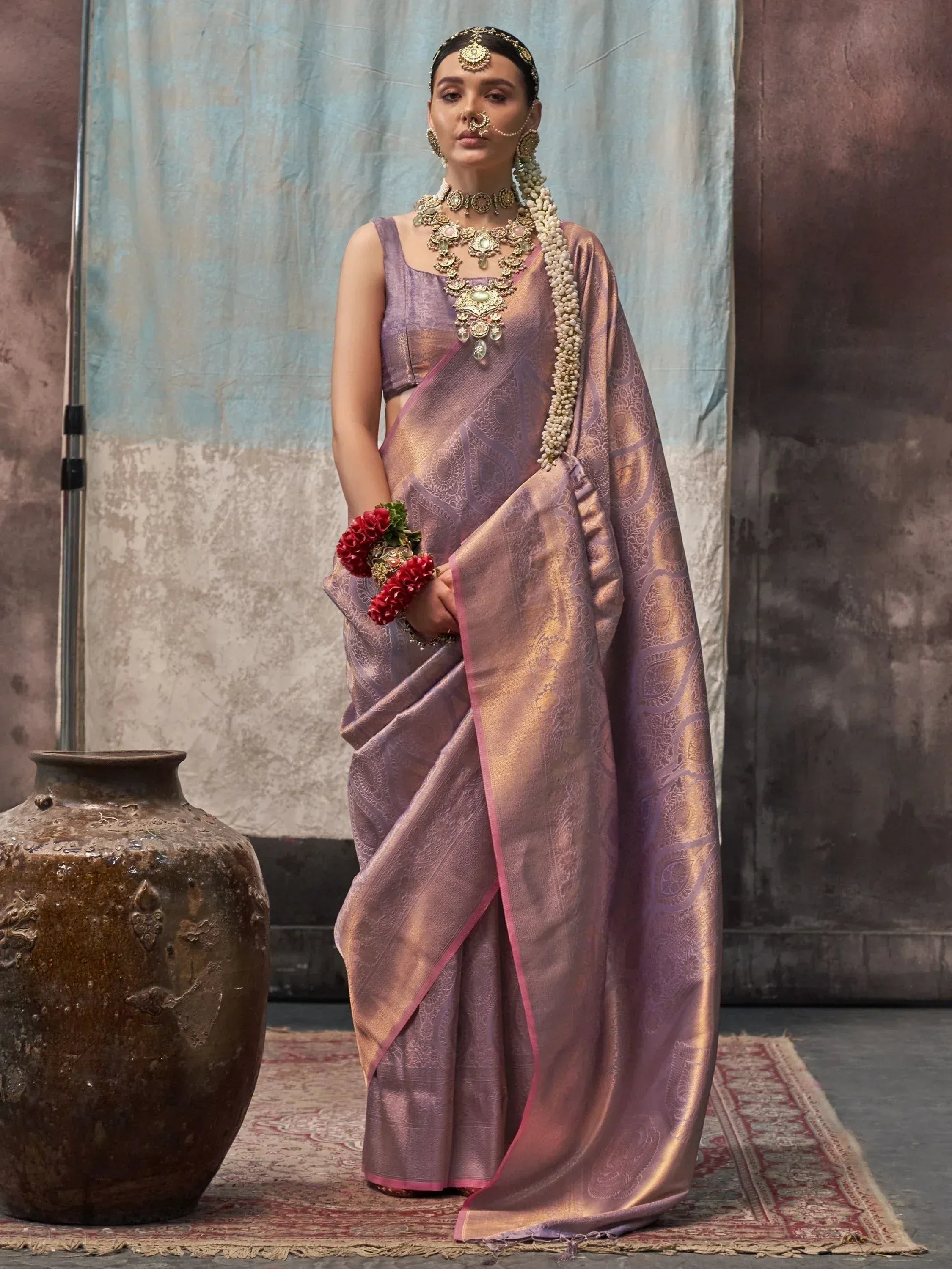 Elegant lavender saree with gold paisley weave, traditional Indian bridal jewelry, and floral garland for ethnic wear.