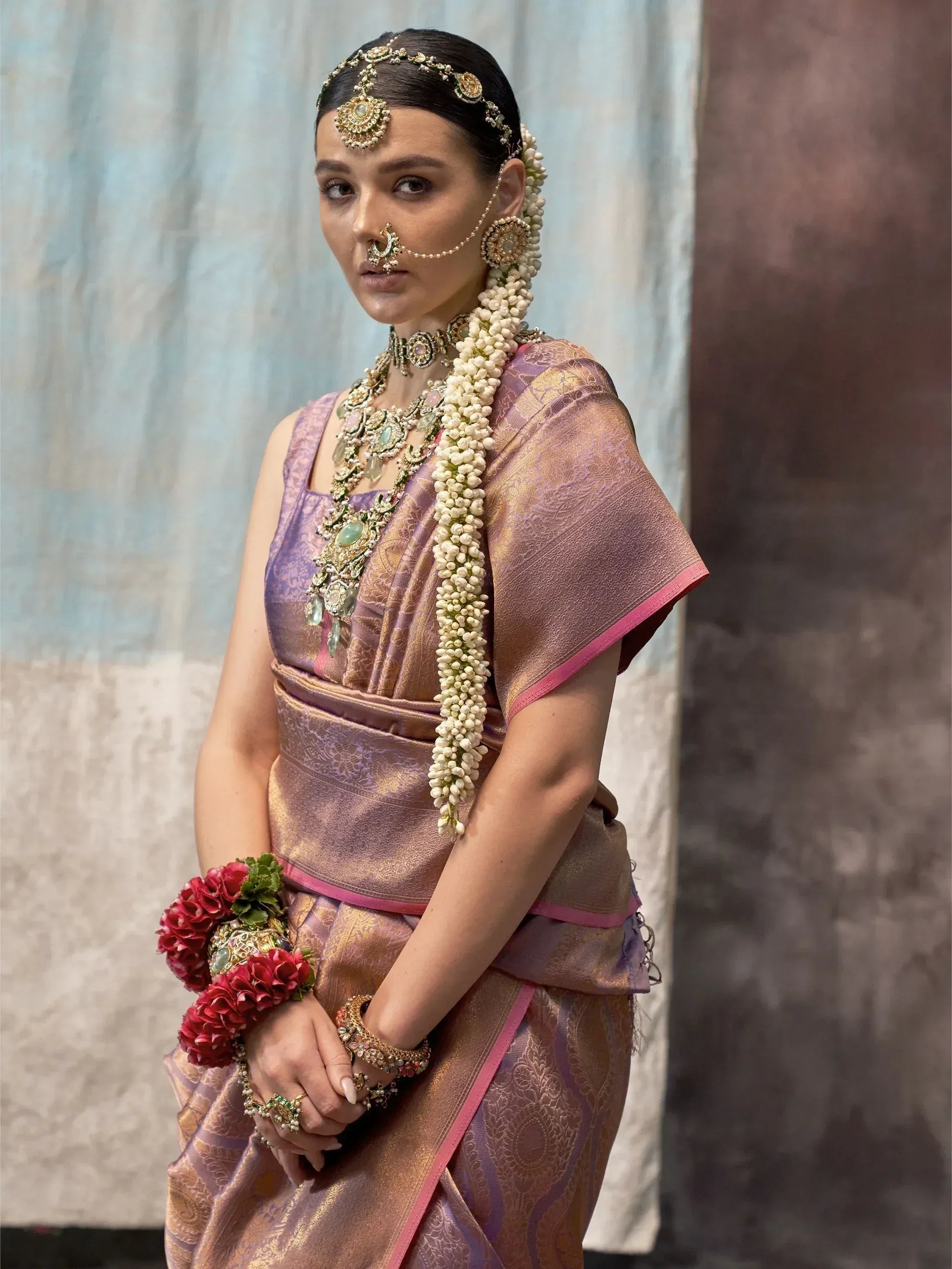 Woman in traditional Indian saree with gold jewelry and floral garland, perfect for ethnic occasions.