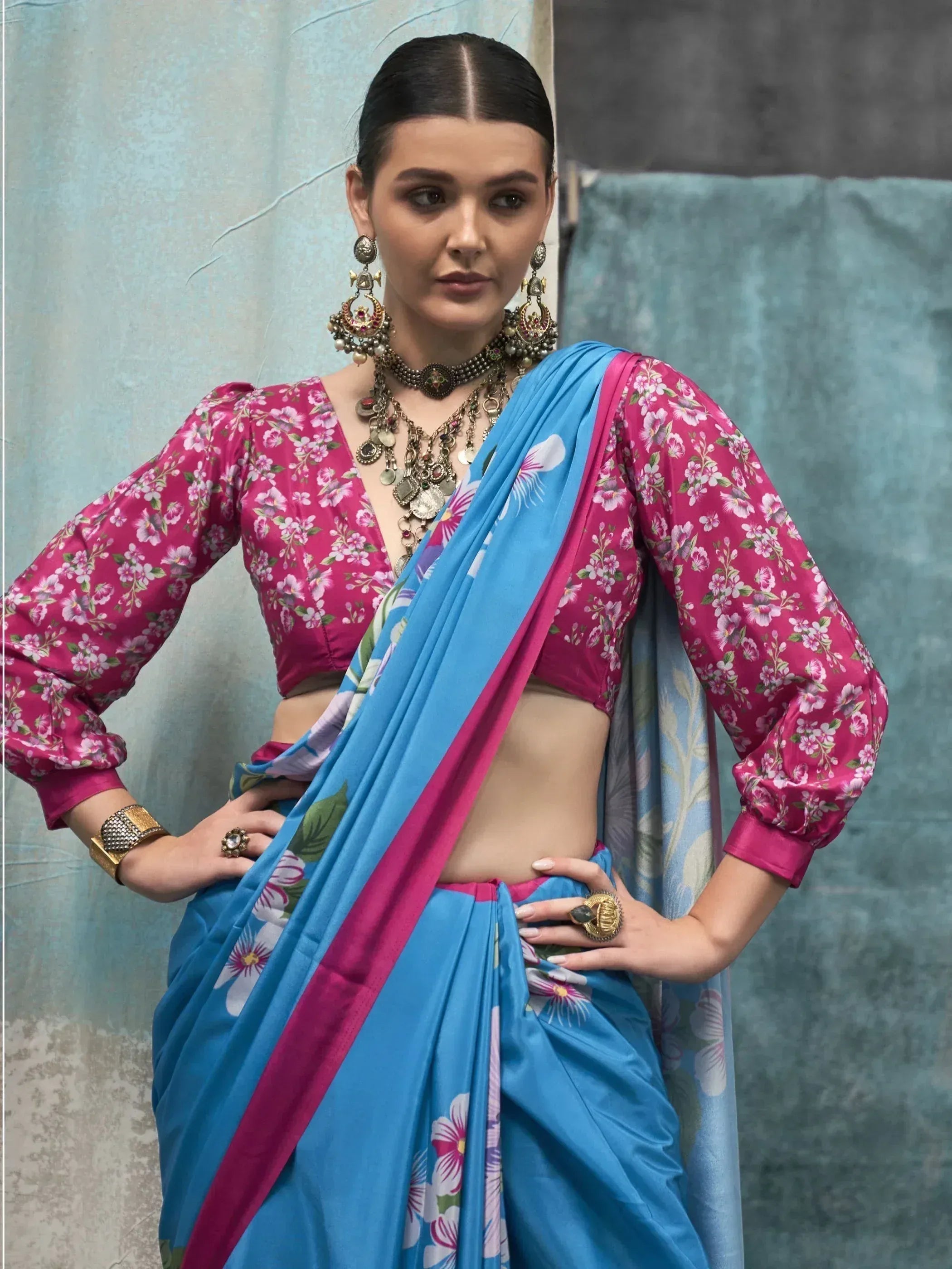 Woman in vibrant pink floral blouse with blue printed saree, styled with ethnic jewelry for Indian ethnic wear