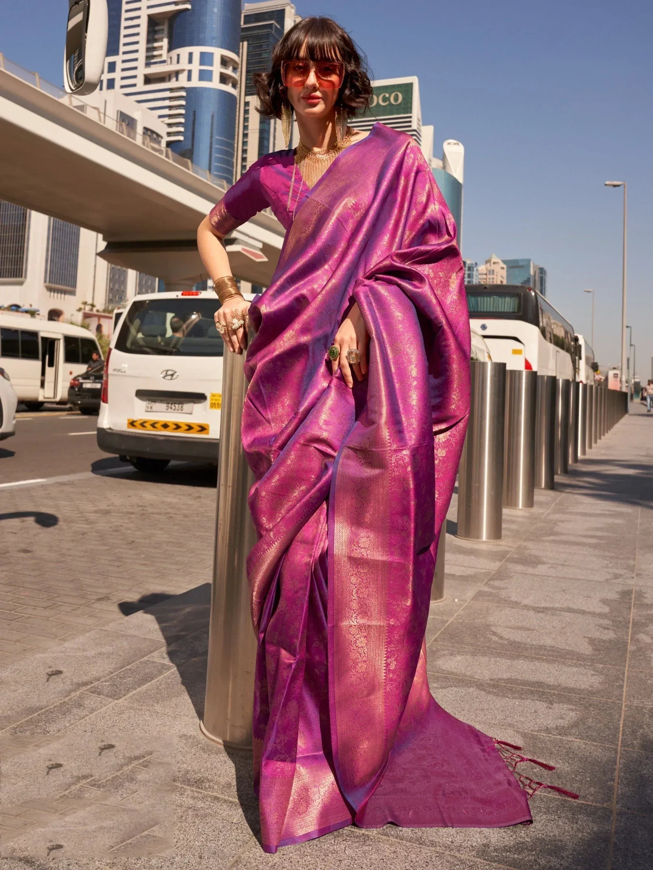 Woman in vibrant purple designer saree with gold zari, styled for modern ethnic wear
