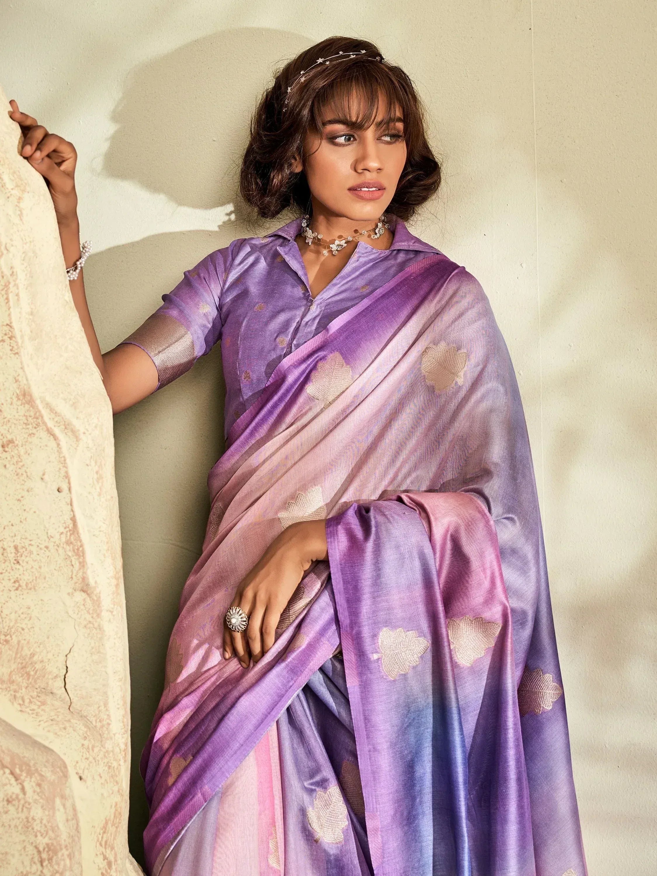 Woman in elegant purple ombre saree with gold leaf motifs, styled with floral jewelry for Indian ethnic wear