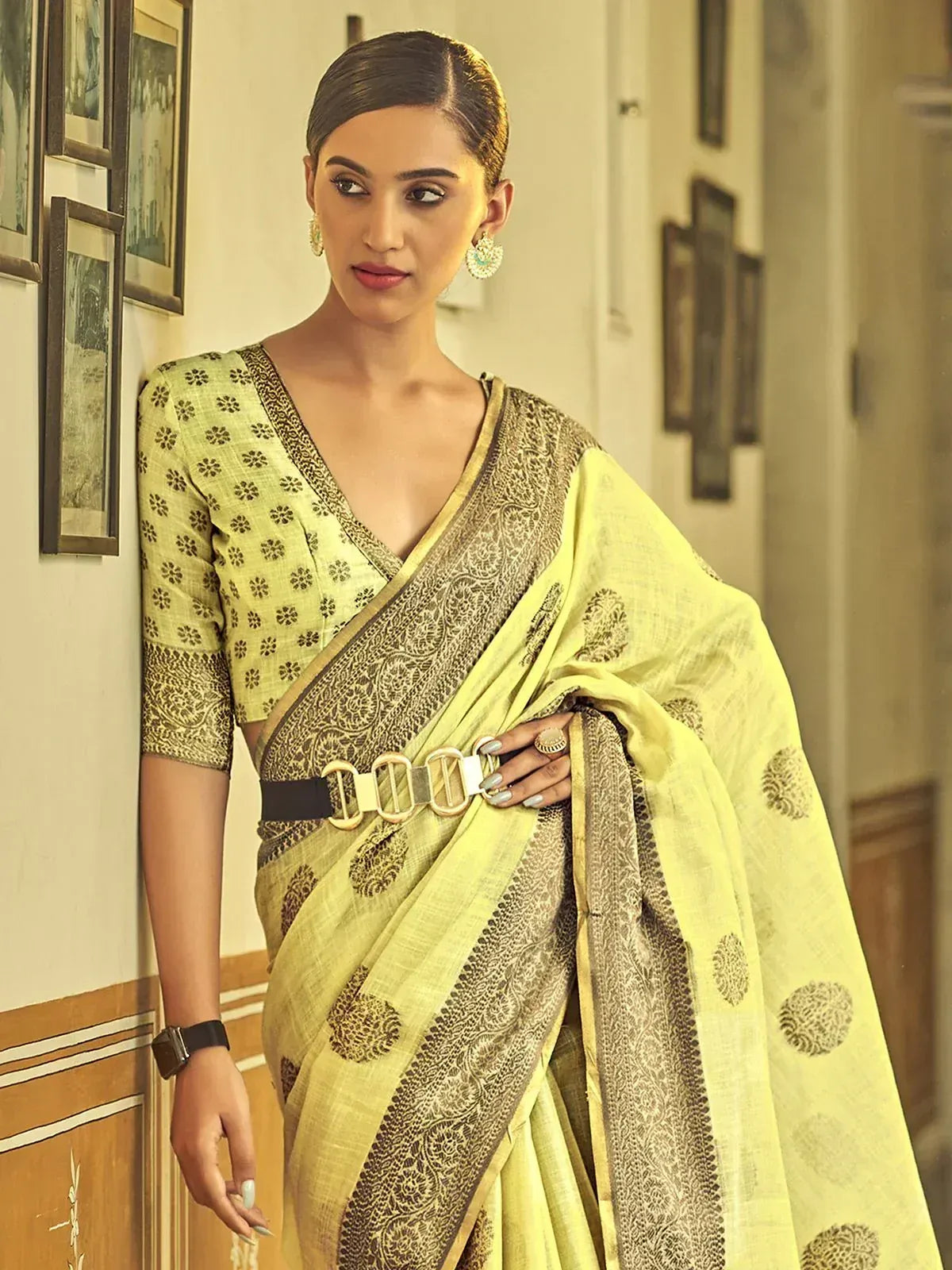 Yellow printed saree with black border, paired with matching blouse and belt, styled for ethnic wear.