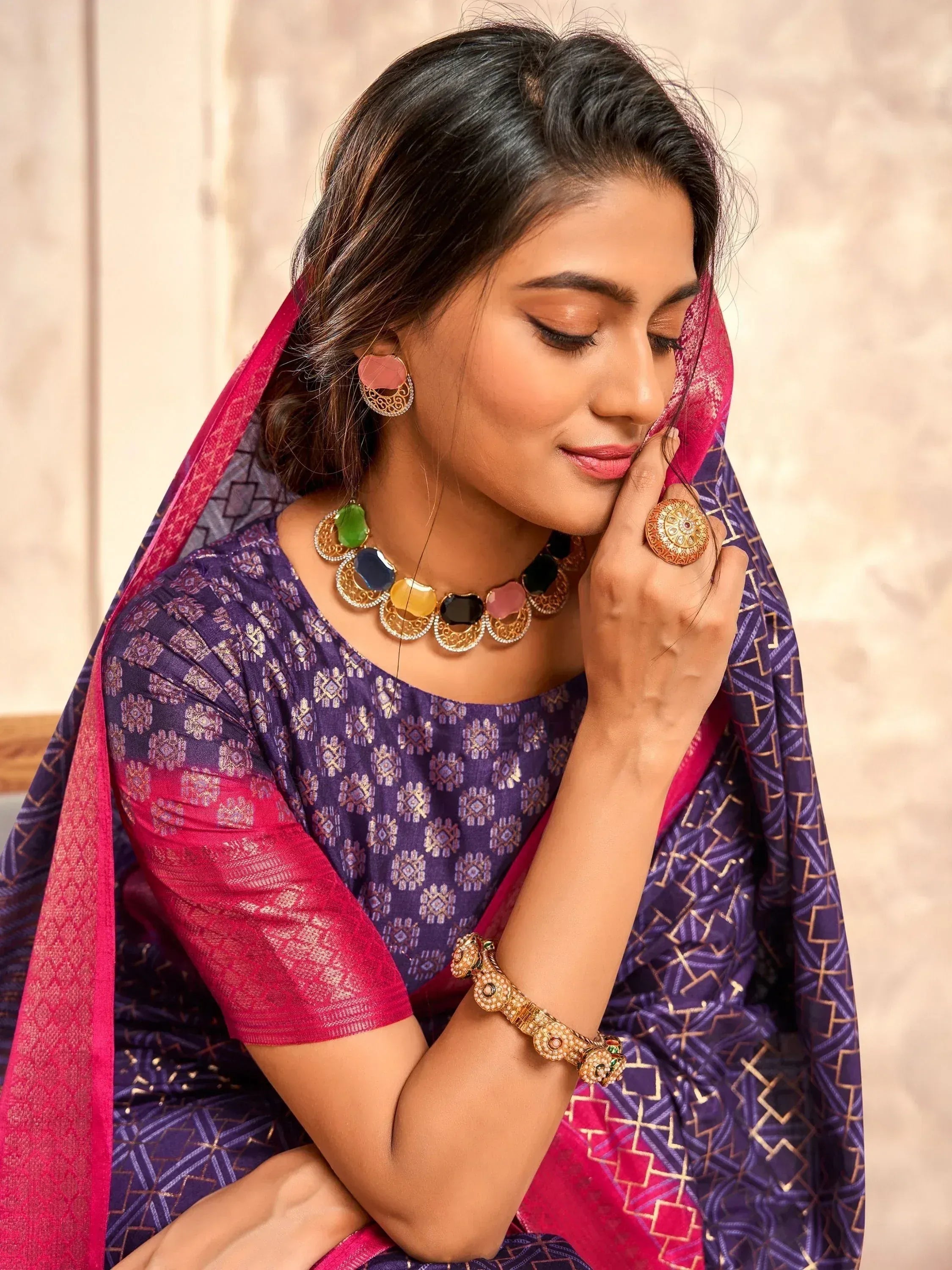 Woman in purple and pink ethnic saree with gold jewelry, traditional Indian attire