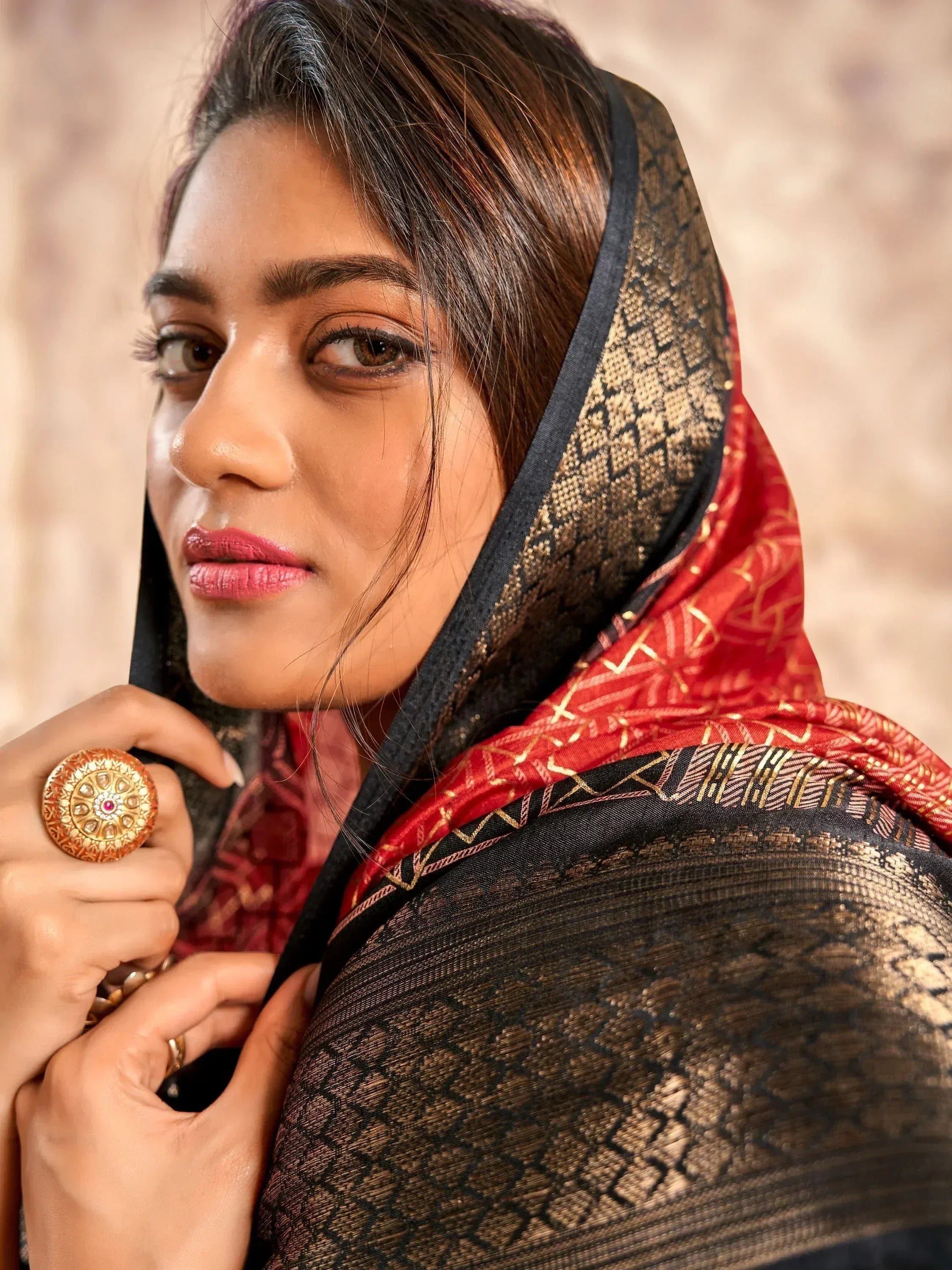 Woman in elegant black and red ethnic saree with gold patterns, styled with traditional jewelry.