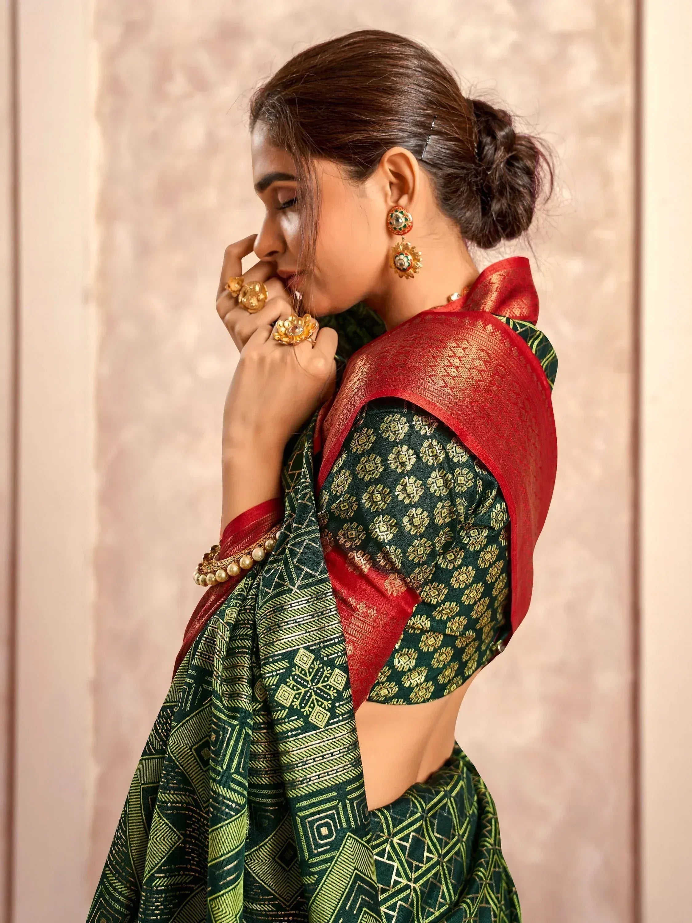 Green and red ethnic saree with gold patterns, paired with traditional jewelry for festive occasions.
