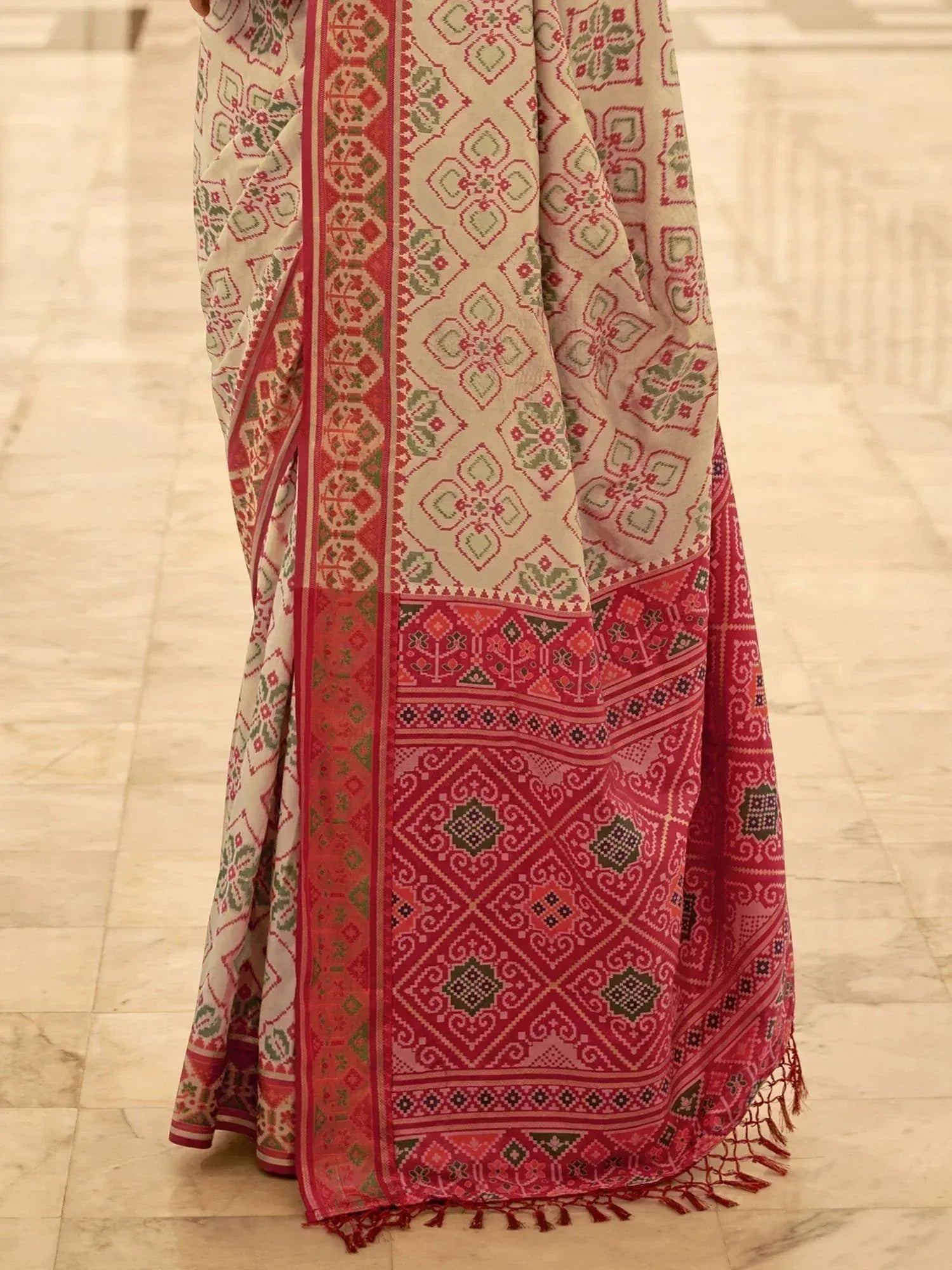 Red and green printed ethnic saree with intricate geometric patterns and tassels, ideal for traditional occasions.
