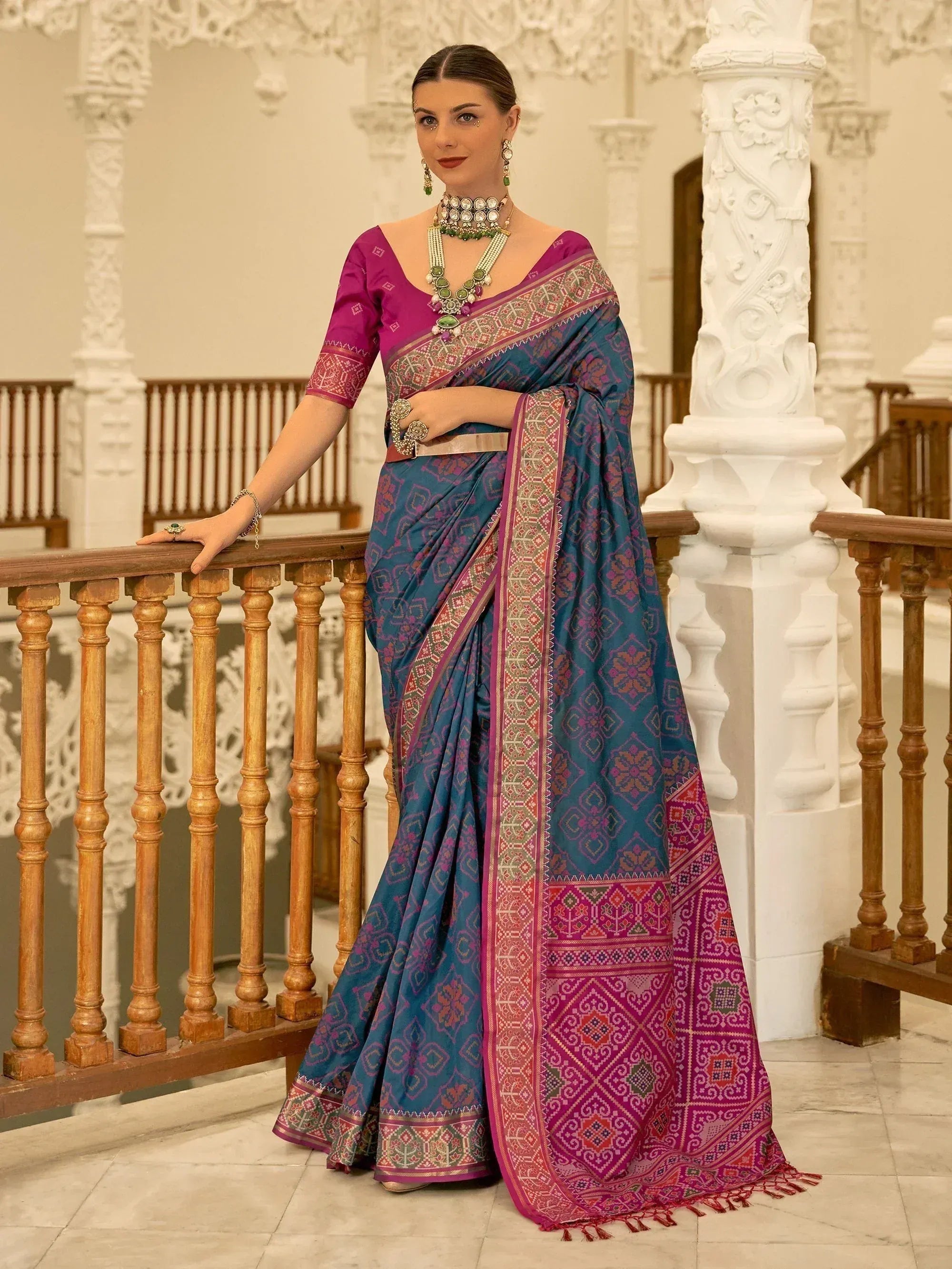 Woman in elegant blue and magenta ethnic saree with intricate patterns, styled with traditional jewelry for festive occasions