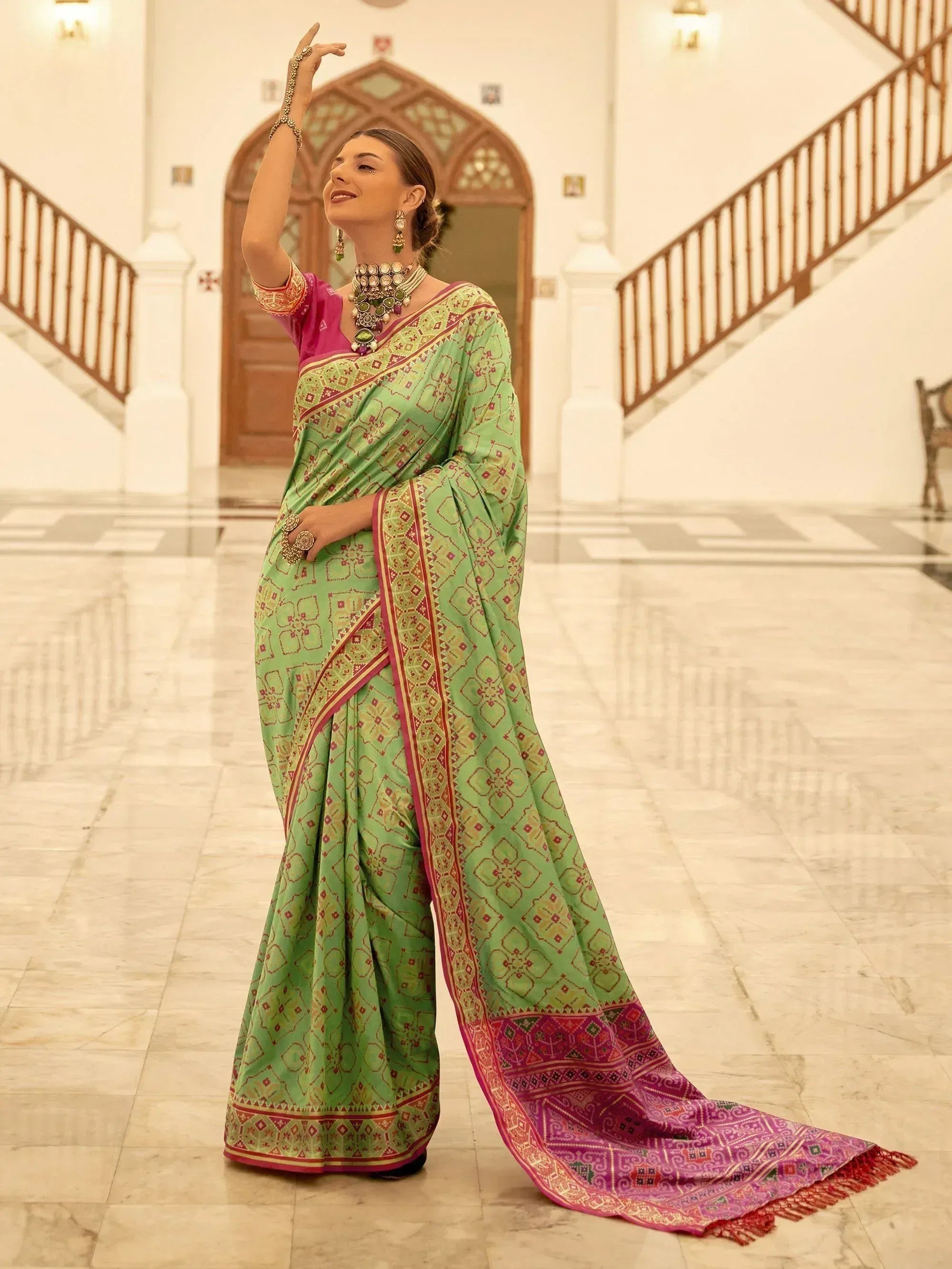 Woman in green printed saree with pink border, traditional Indian ethnic wear, styled with jewelry in palace setting