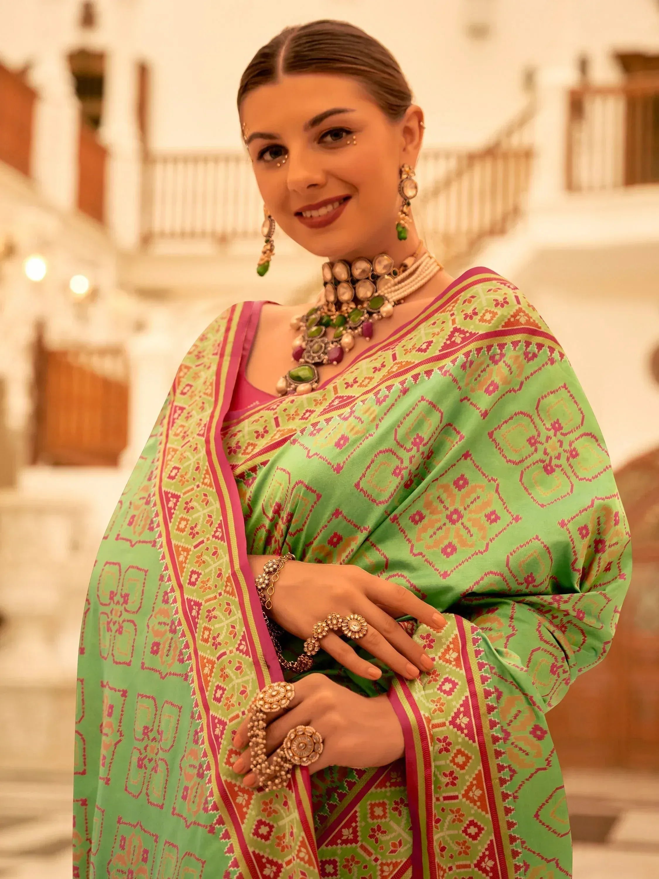 Woman in green printed saree with pink border, traditional Indian jewelry, ethnic wear