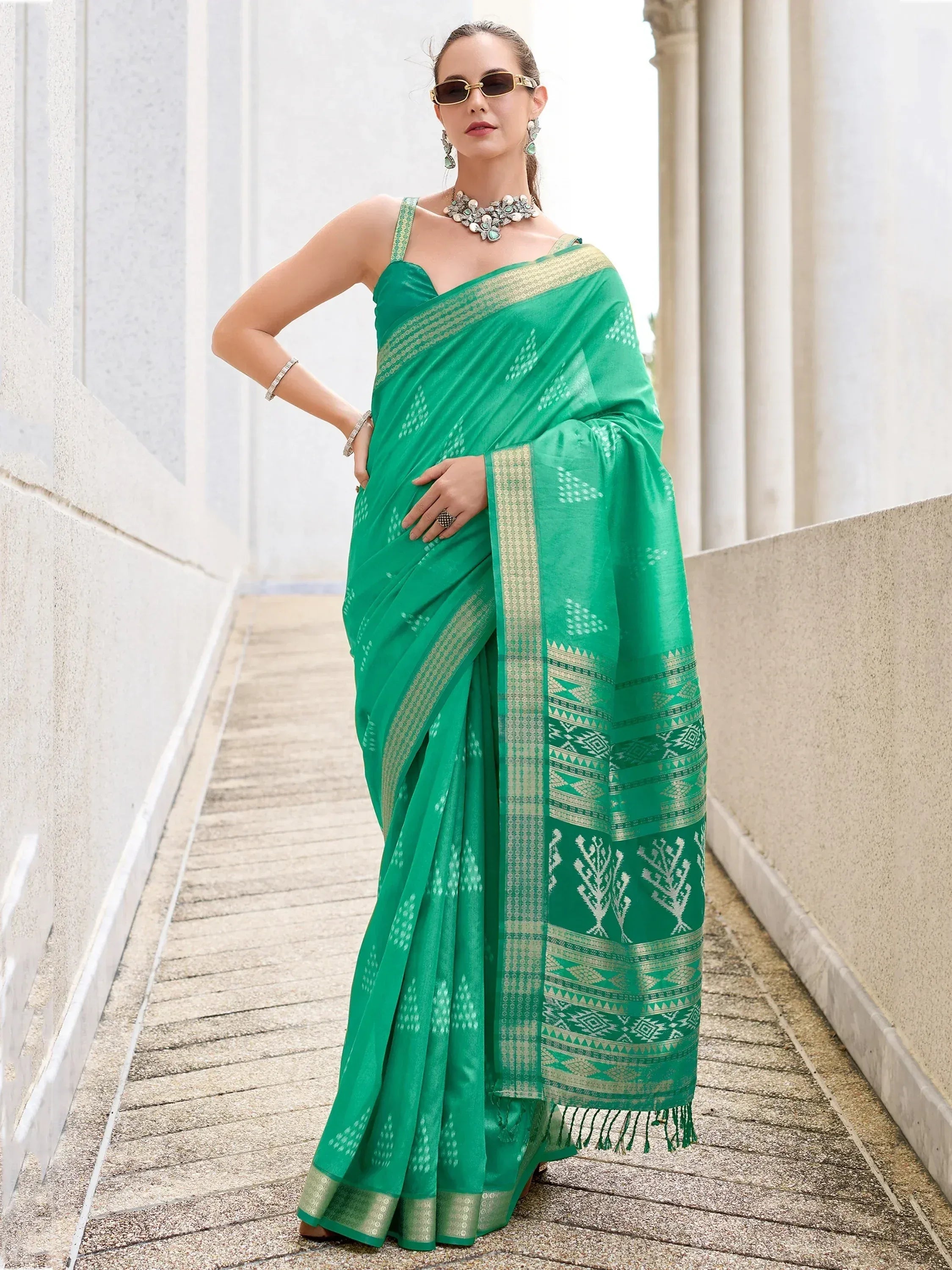 Emerald green ethnic saree with gold border and geometric print, styled with statement jewelry for festive occasions