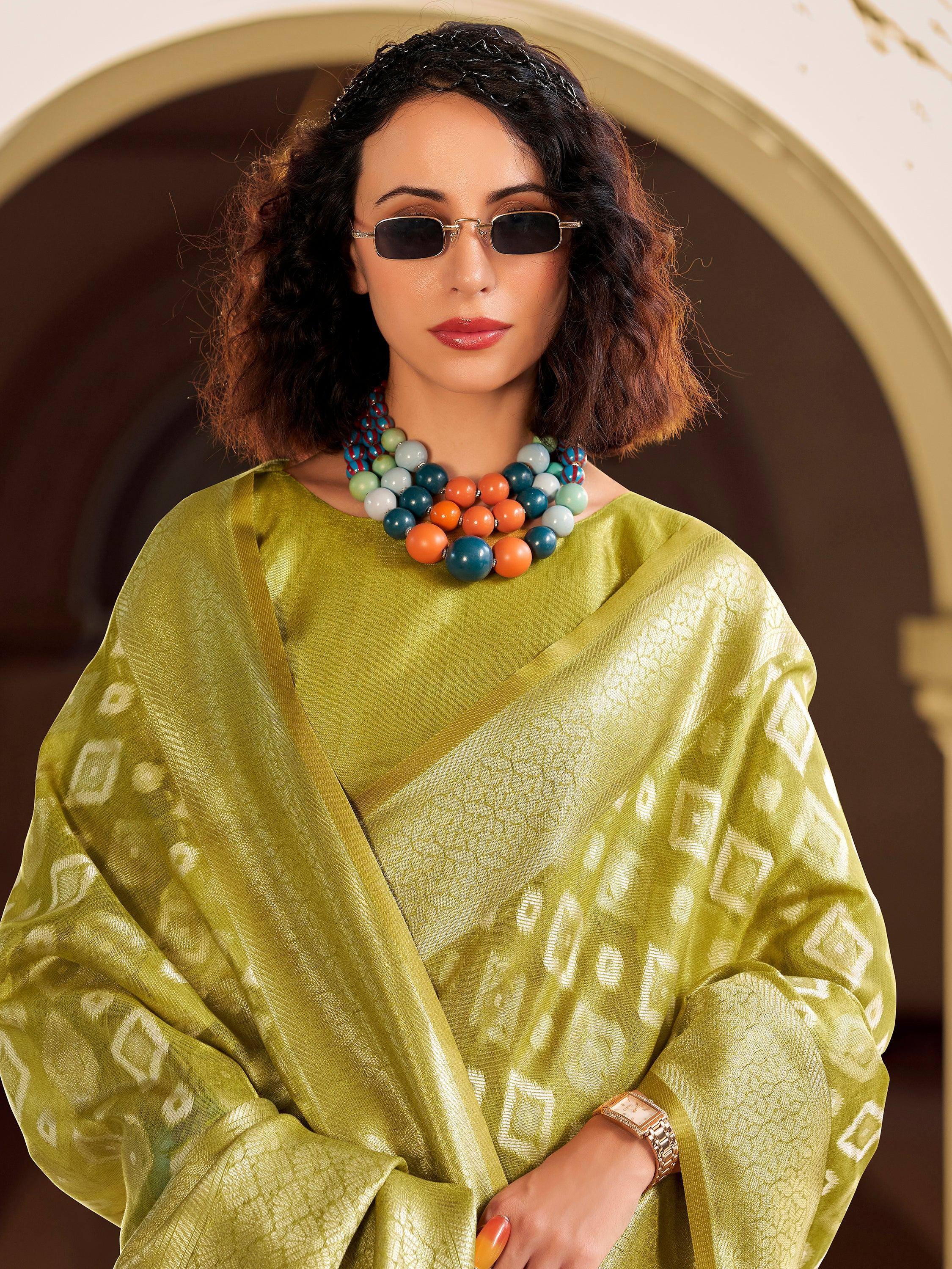 Stylish woman in olive green ethnic gown with geometric print, bold beaded necklace, and sunglasses