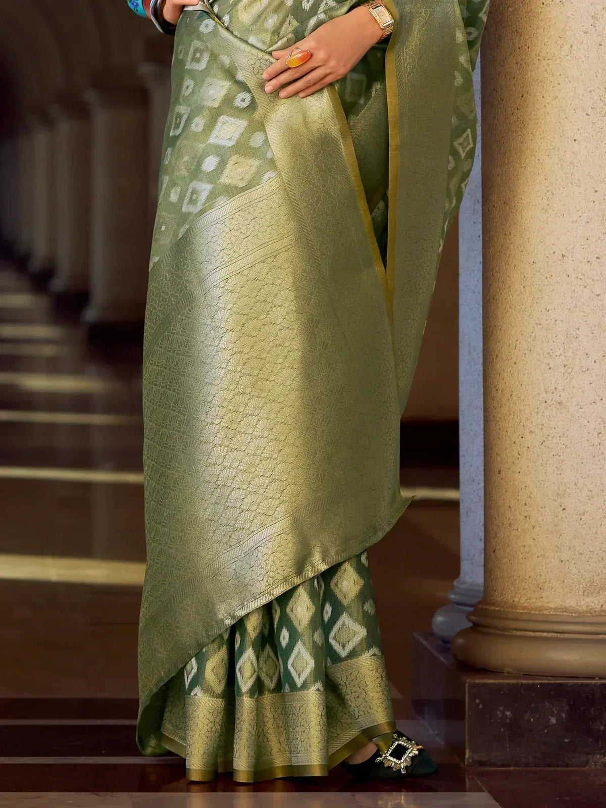 Olive green designer saree with geometric print and gold border, styled with ethnic blouse and heels