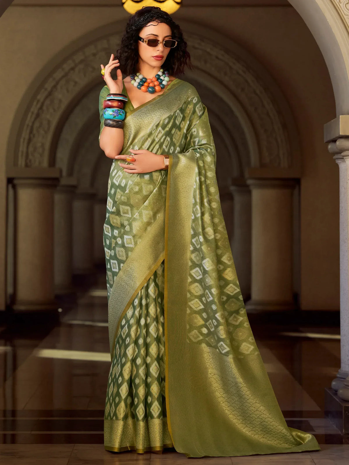 Olive green ethnic saree with geometric print, gold border, paired with statement jewelry for festive occasions