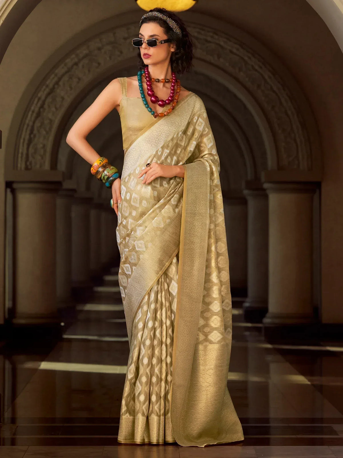 Elegant gold designer saree with geometric print, paired with statement jewelry and sunglasses for a modern ethnic look.