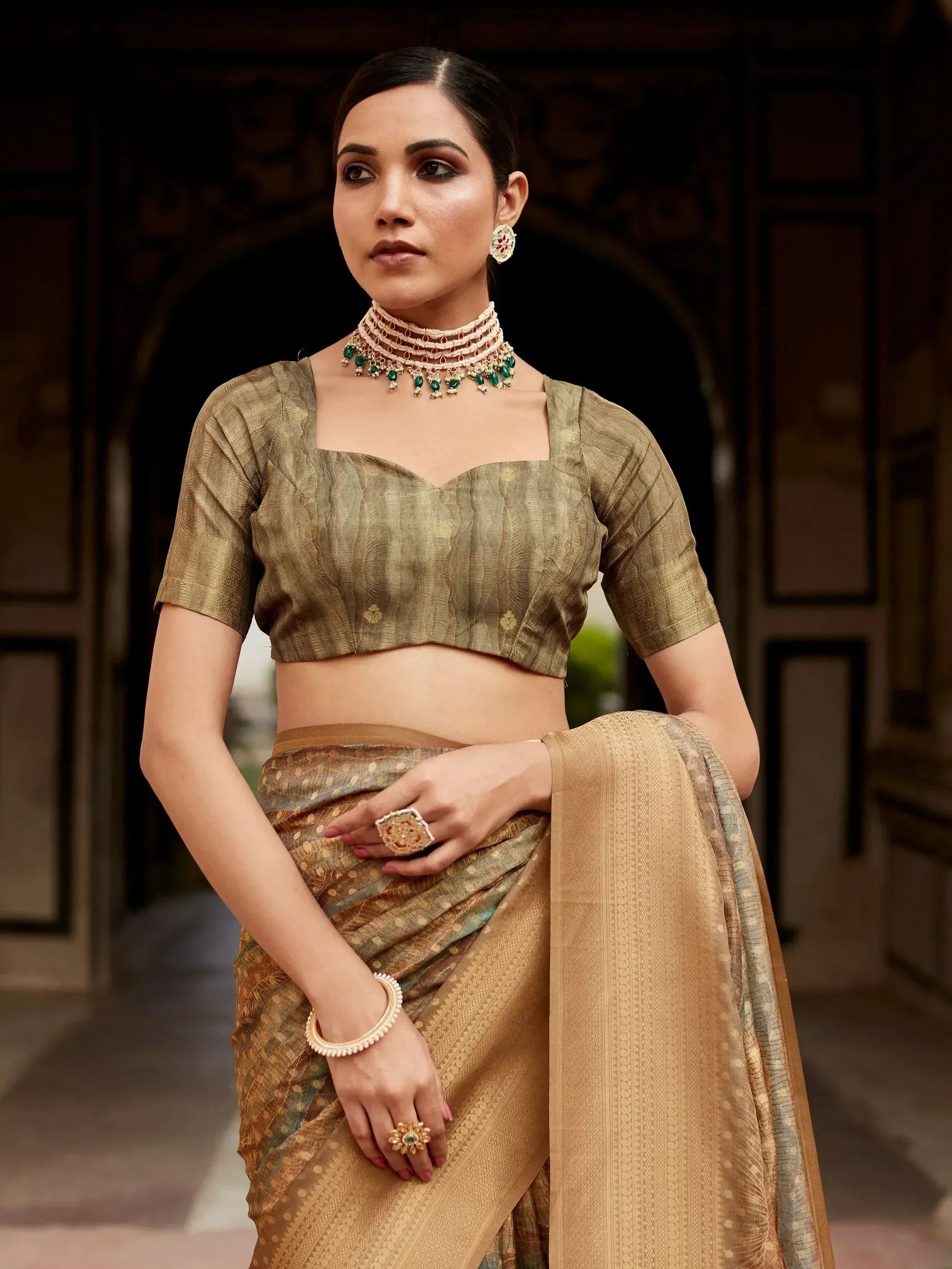 Elegant woman in olive green designer saree with gold embroidery, paired with traditional jewelry for ethnic wear