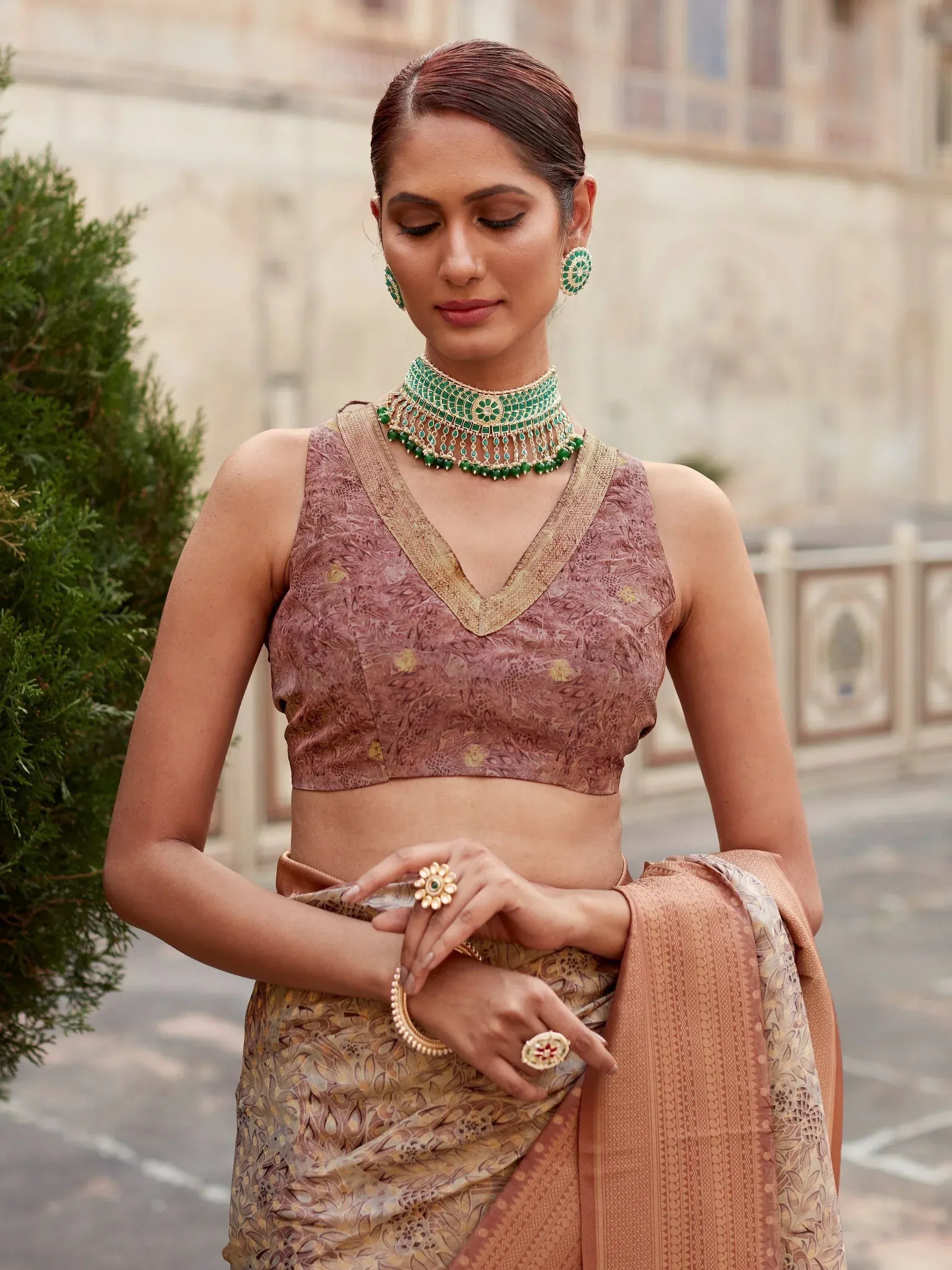 Woman in elegant Indian saree with floral blouse, green jewelry, and traditional ethnic wear