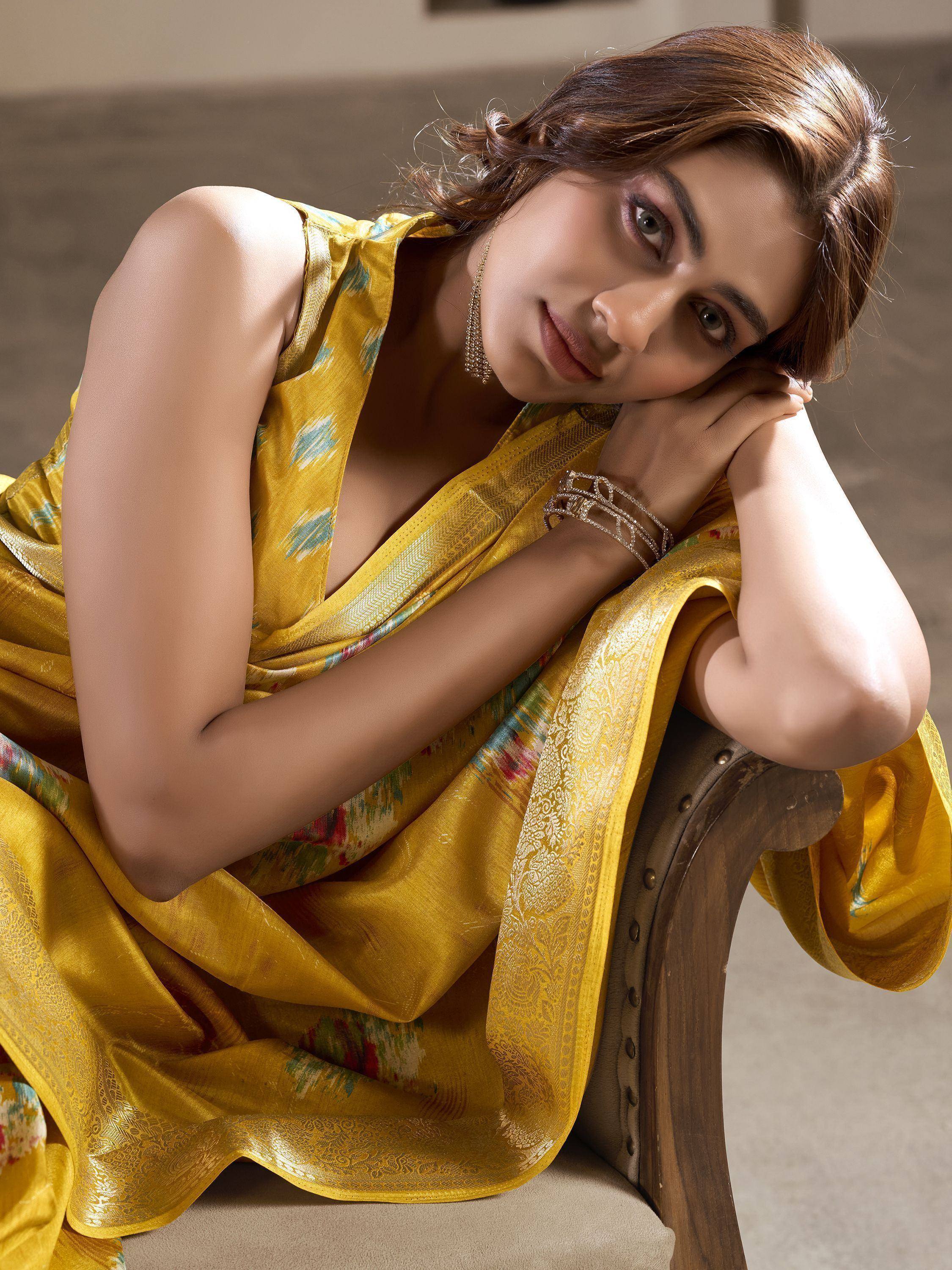 Woman in elegant yellow designer saree with floral print and golden border, styled for Indian ethnic wear