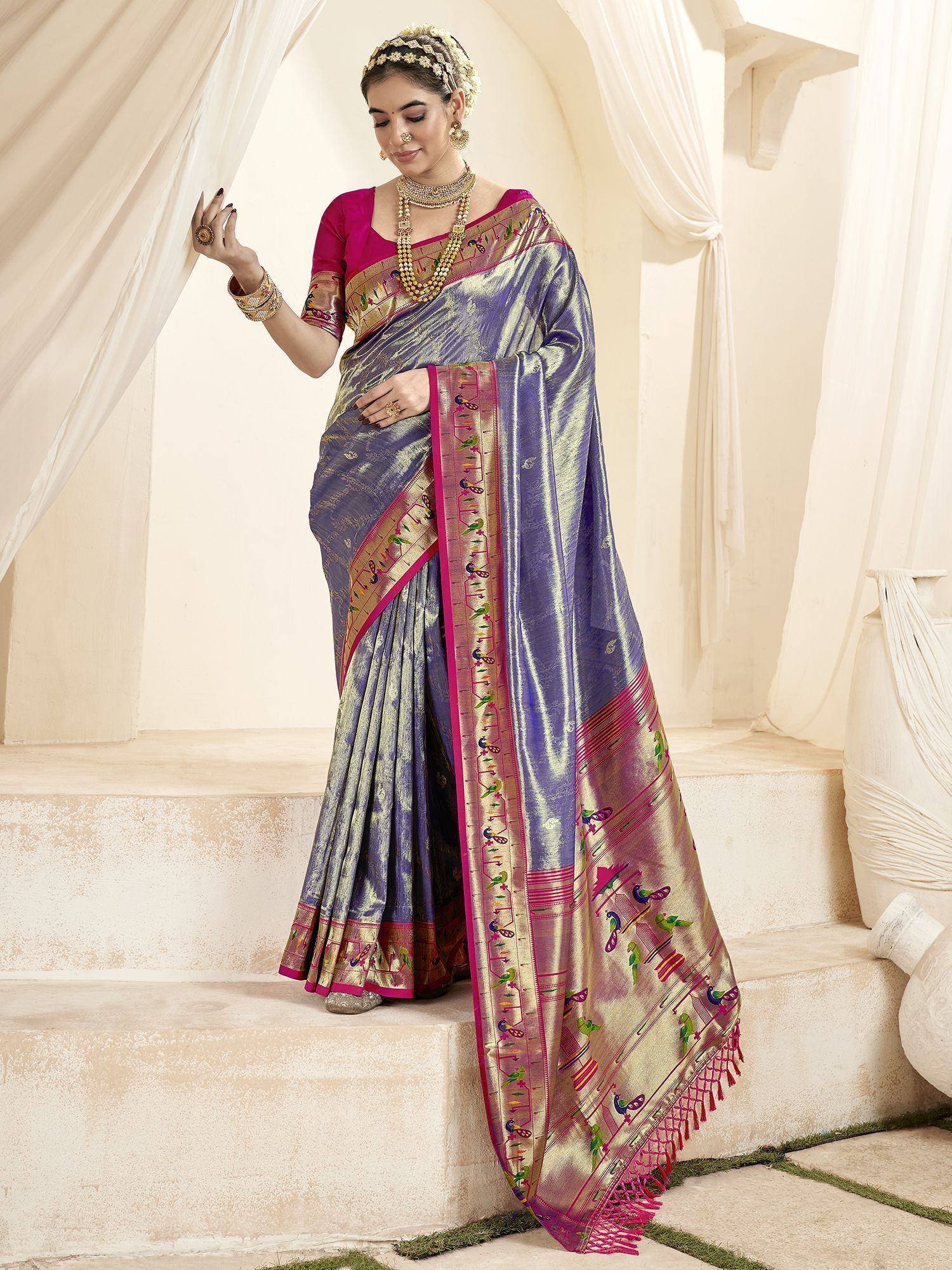 Woman in purple and gold designer saree with bird motifs, pink border, and traditional jewelry, ideal for ethnic occasions.