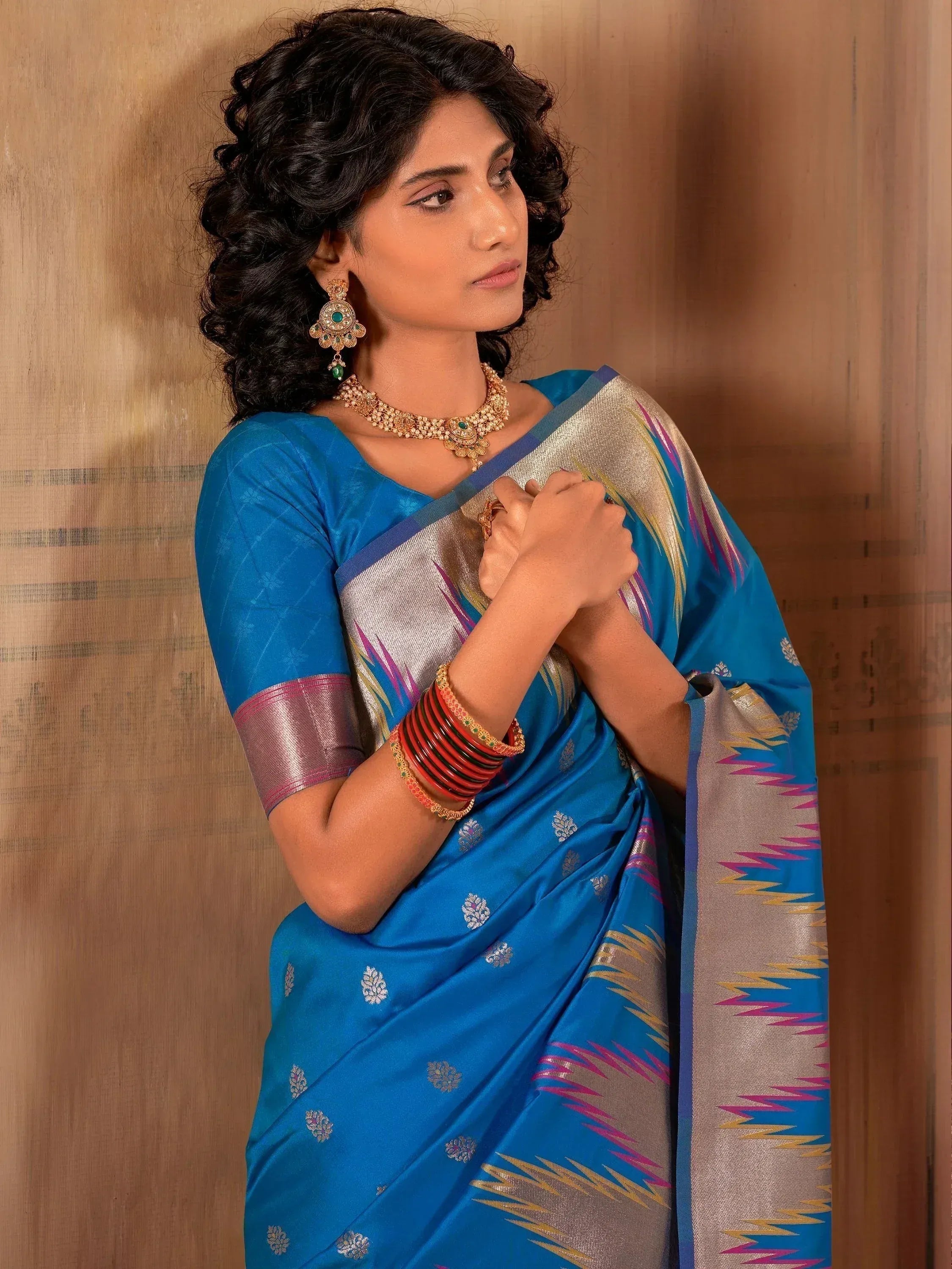 Blue designer saree with silver border and floral motifs, paired with traditional jewelry for ethnic wear