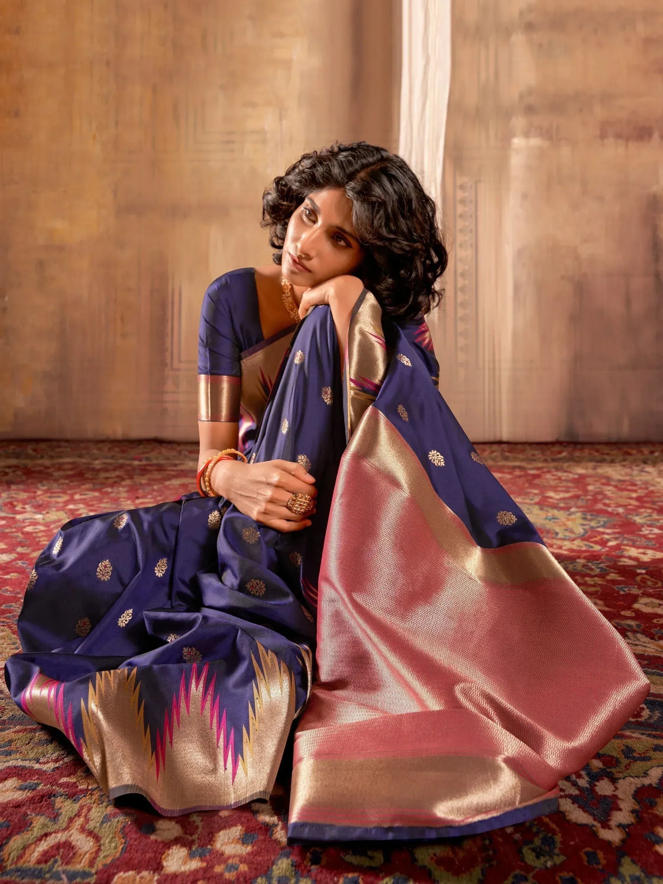 Woman in elegant navy blue saree with gold and pink border, traditional Indian ethnic wear