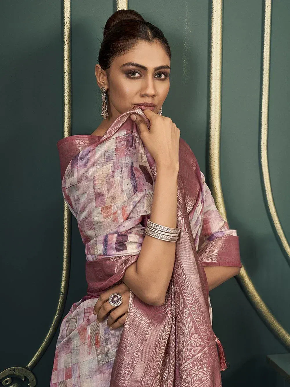 Woman in elegant pink printed saree with gold border, styled with traditional jewelry for ethnic occasions