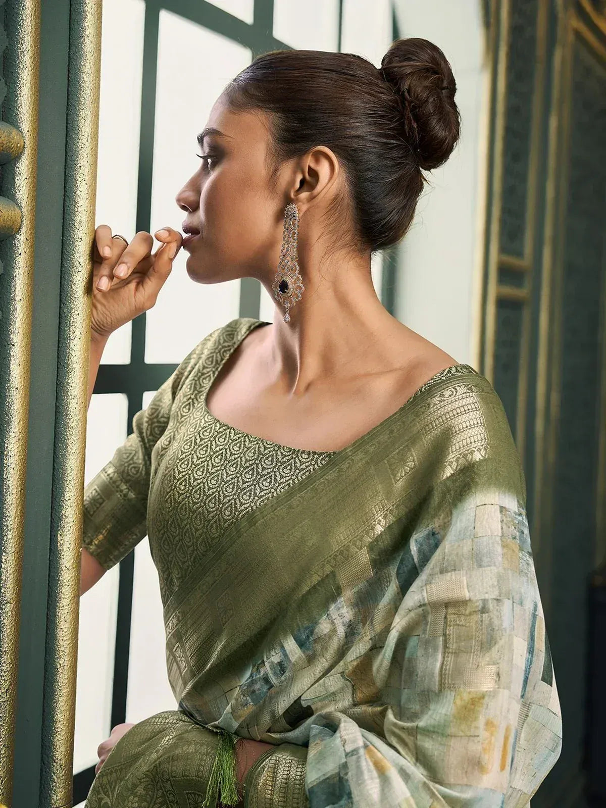 Olive green designer saree with intricate patterns and statement earrings, perfect for ethnic occasions