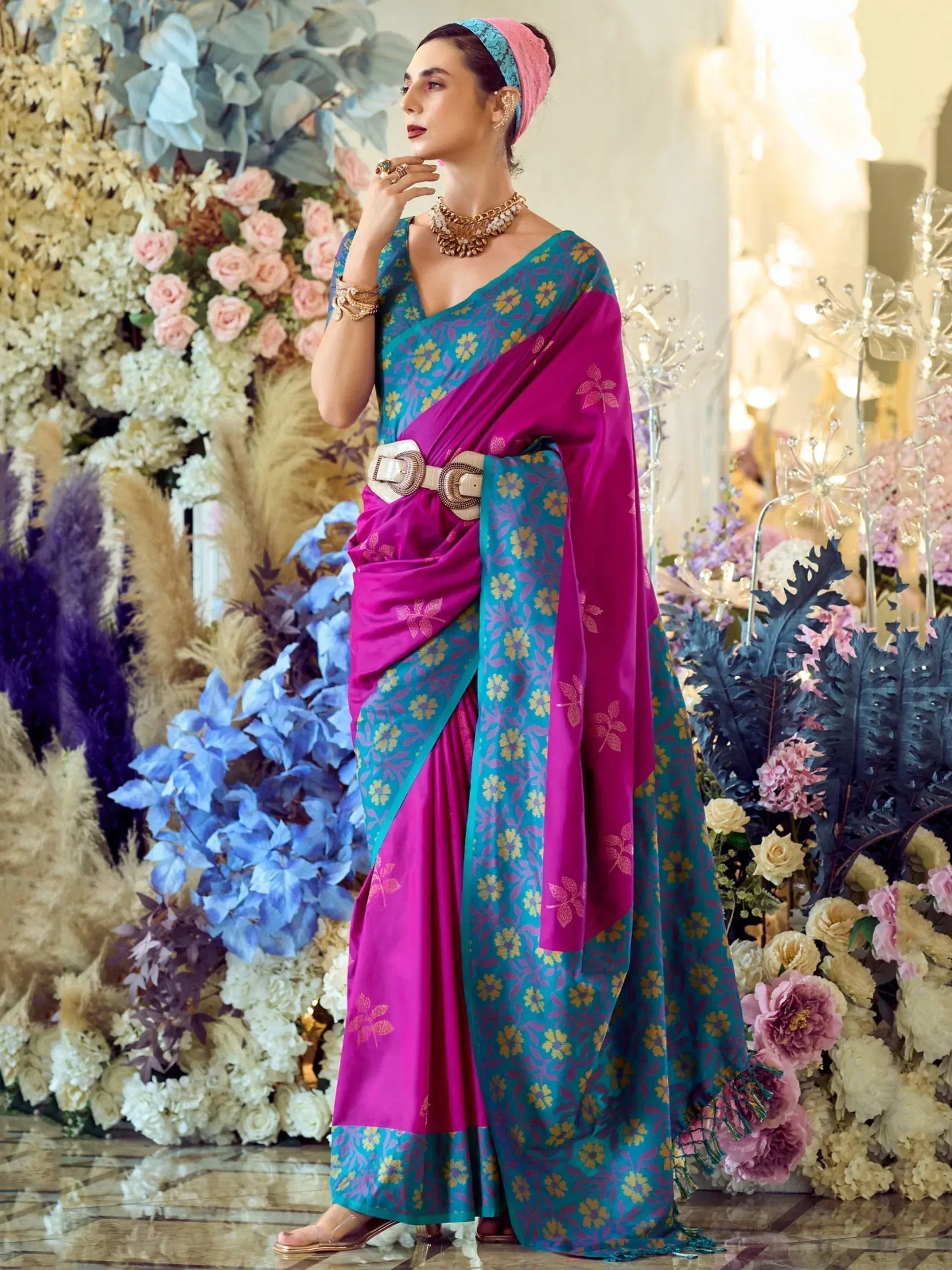 Woman in vibrant pink and teal floral saree with gold belt, styled for Indian ethnic occasions