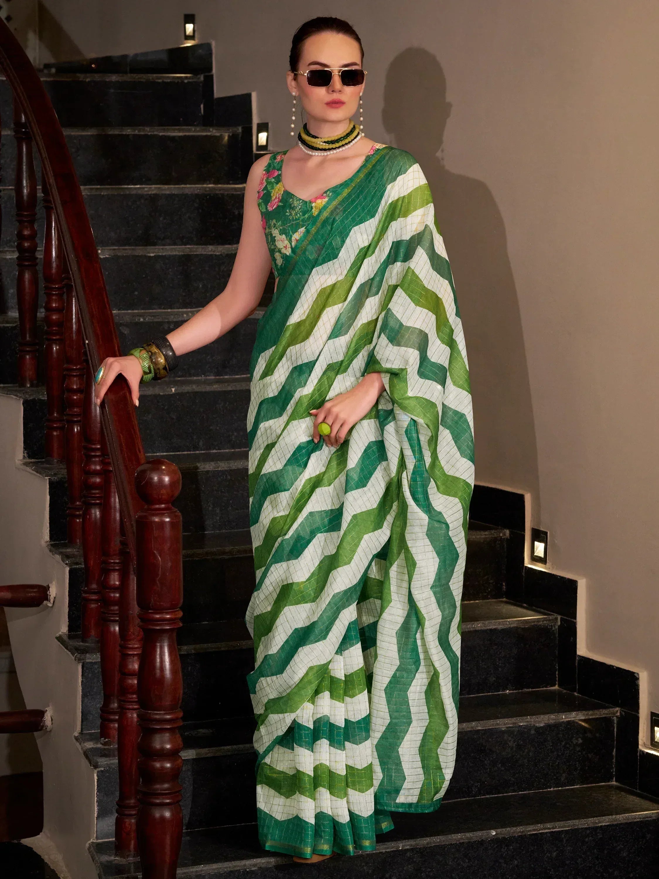 Green and white zigzag pattern saree with floral blouse, styled with sunglasses and jewelry on stairs