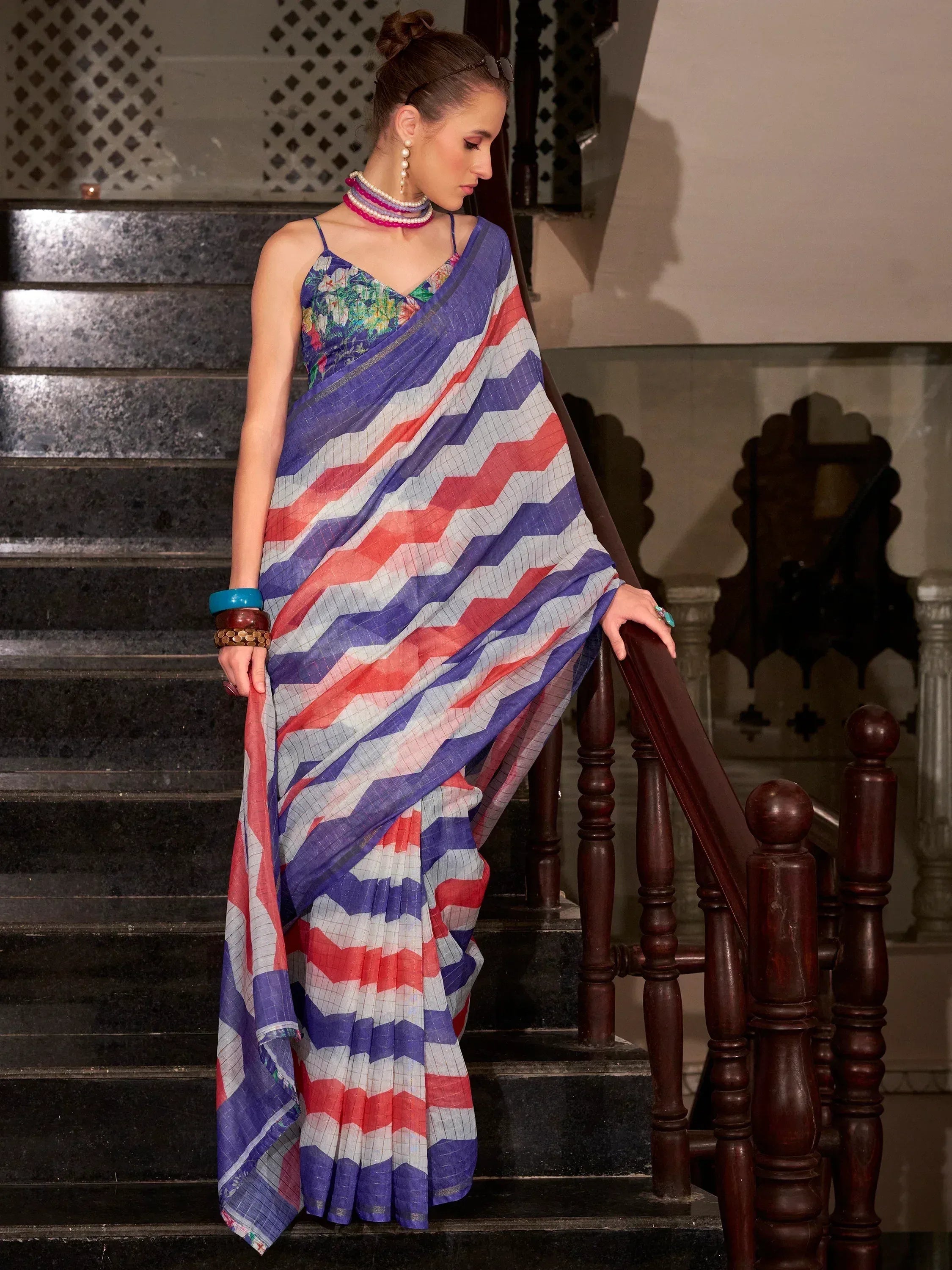 Woman in colorful zigzag saree with floral blouse, standing on staircase