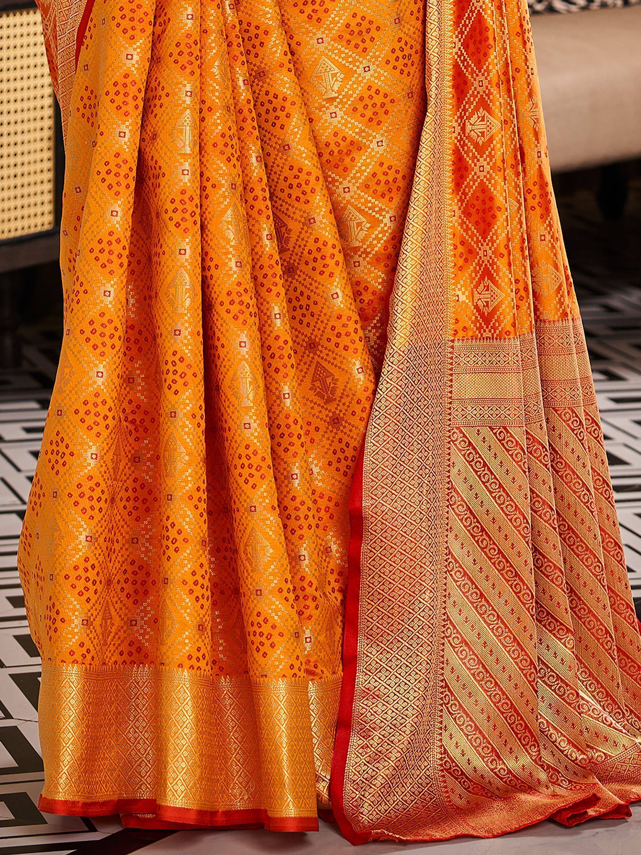 Vibrant orange ethnic saree with intricate red and gold geometric patterns, perfect for festive occasions.