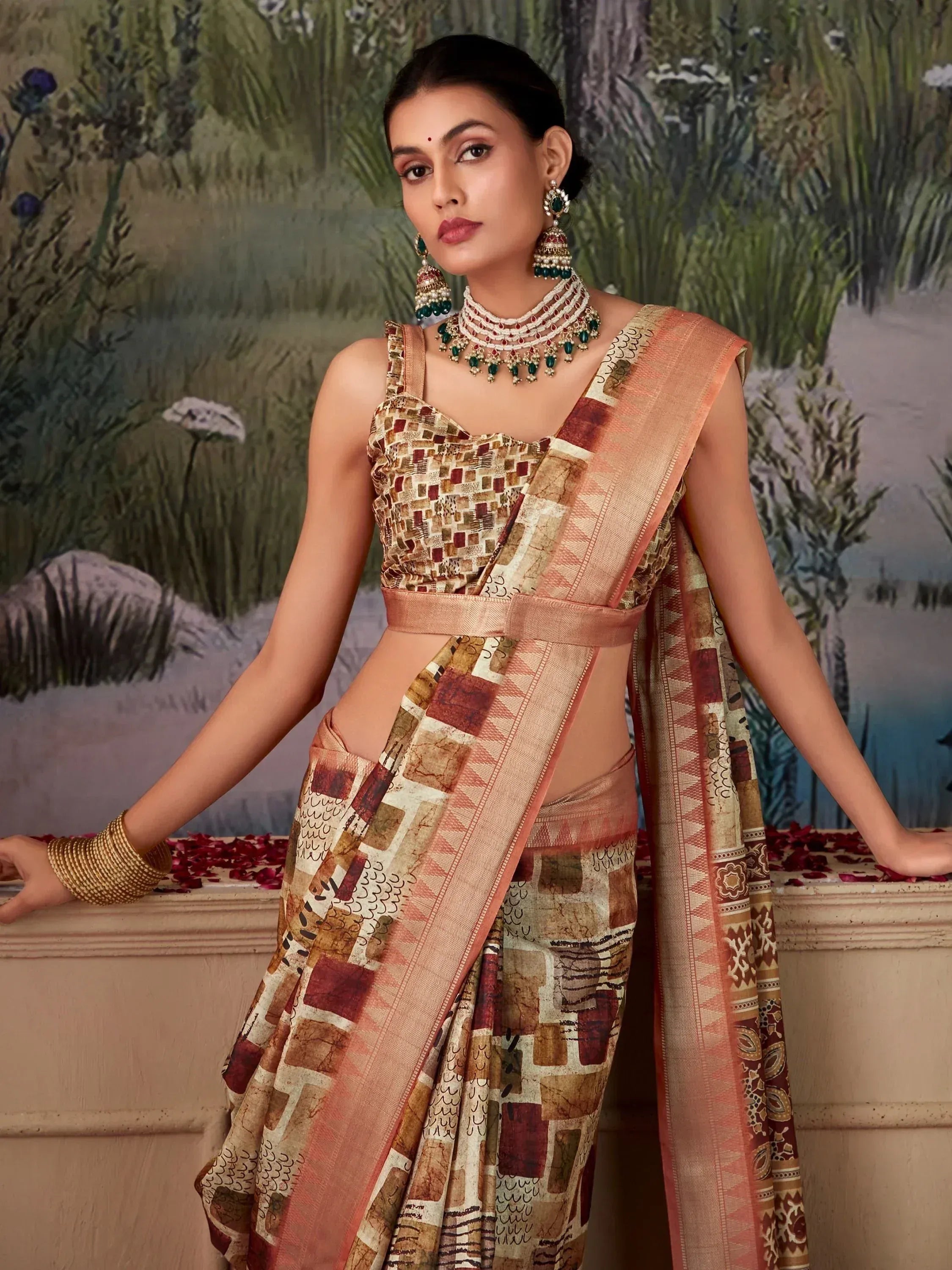 Woman in elegant Indian saree with geometric print, traditional jewelry, and floral backdrop