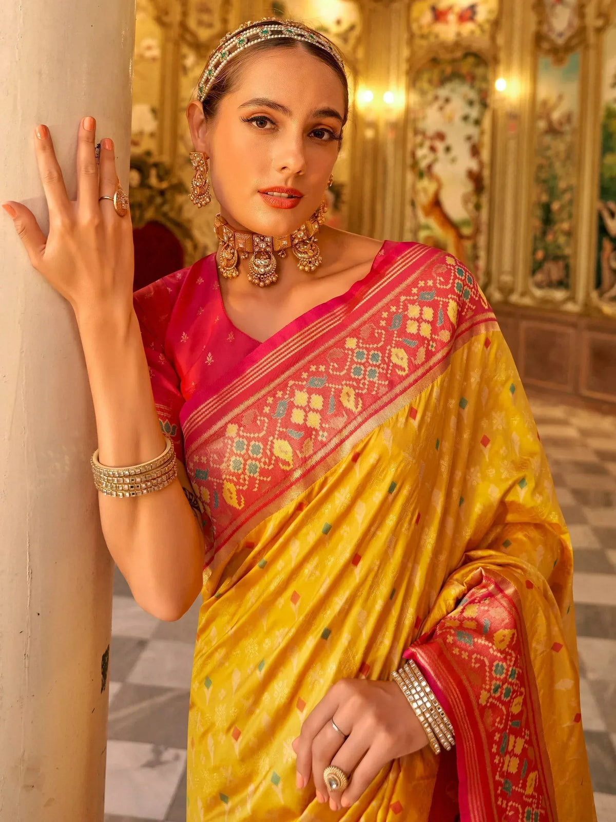 Woman in vibrant yellow and pink ethnic saree with traditional jewelry, perfect for Indian occasions
