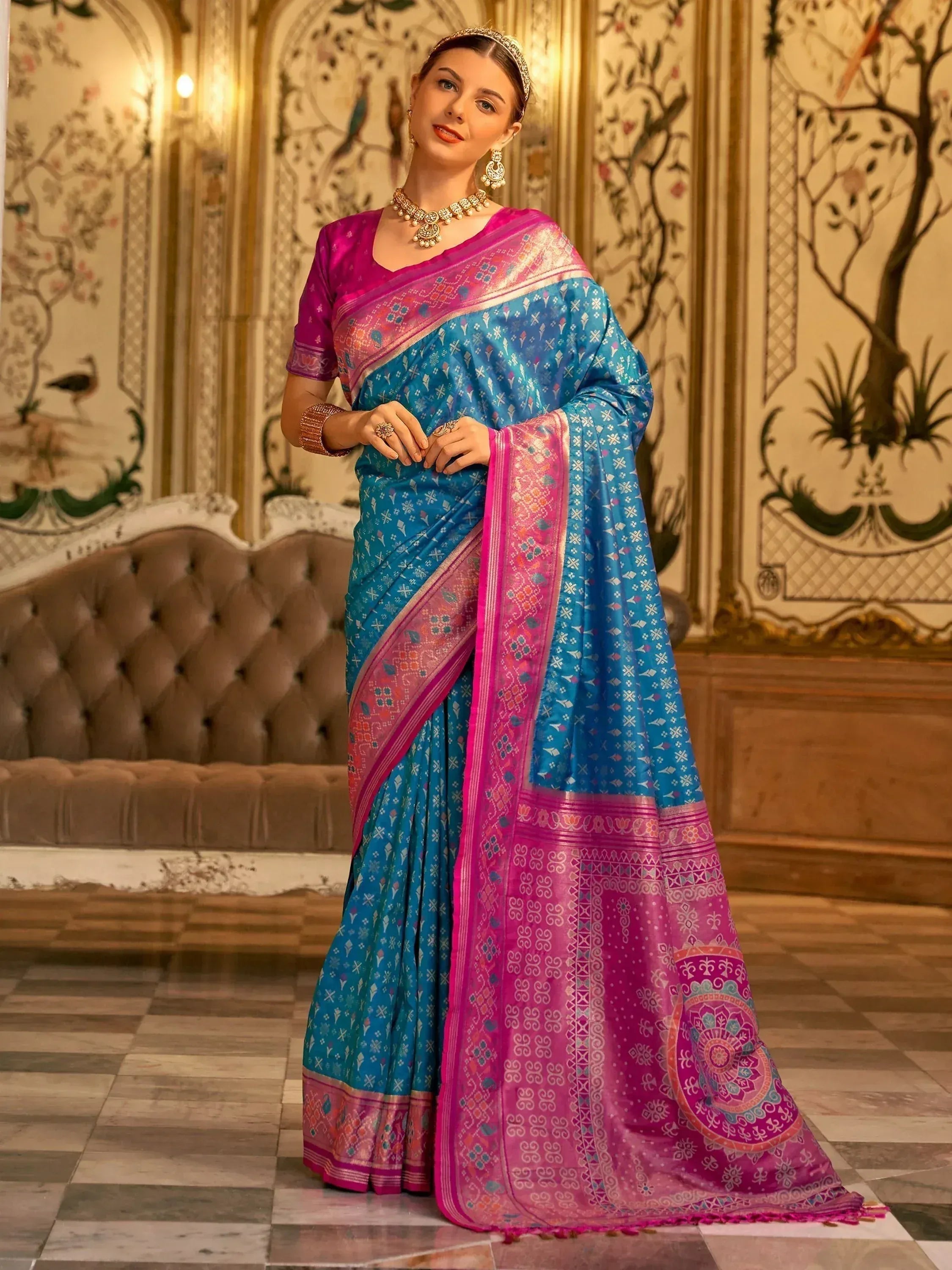 Blue and pink printed saree with ethnic motifs, paired with matching blouse and traditional jewelry