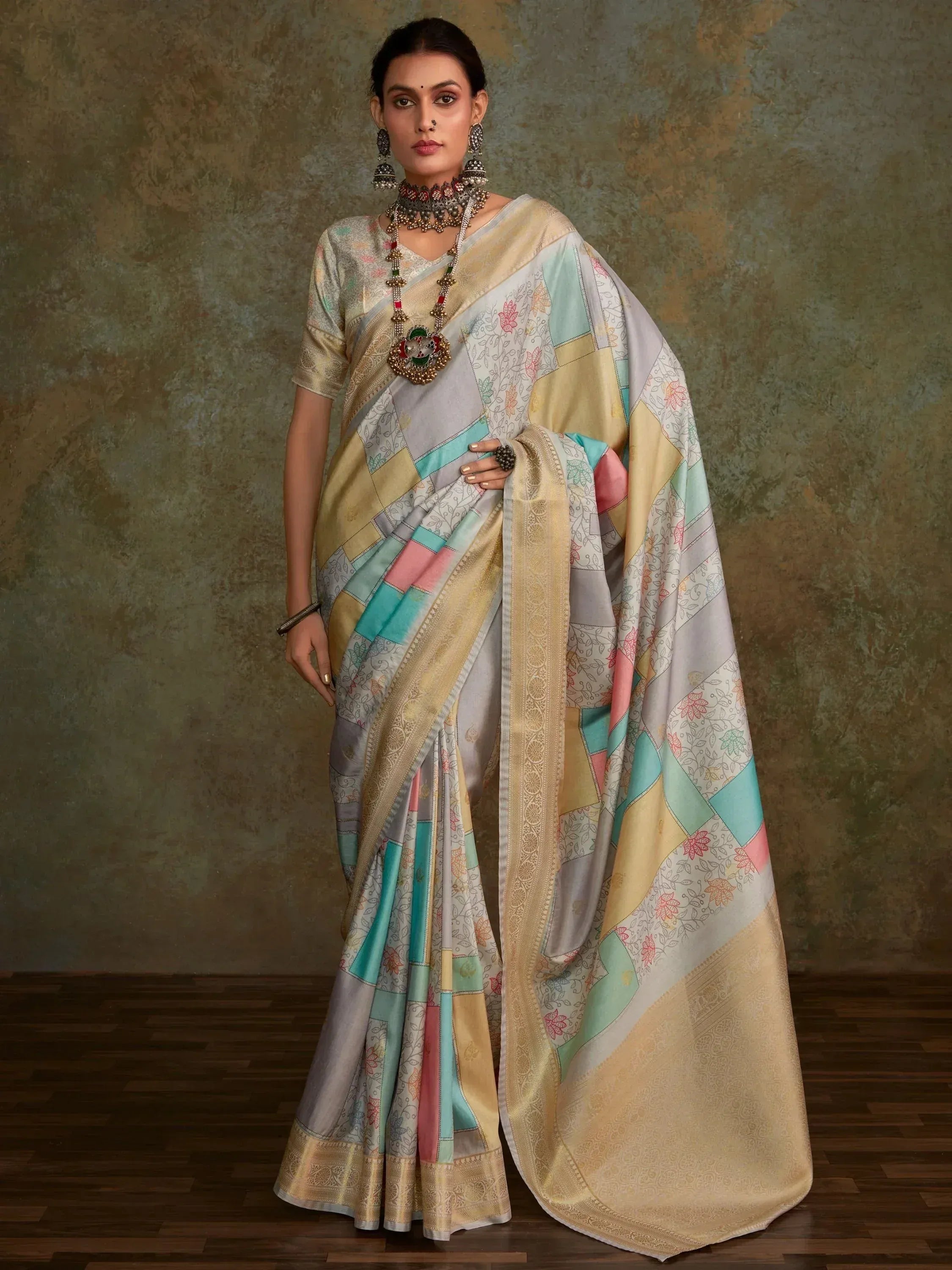 Woman in colorful patchwork saree with floral prints and gold border, styled with ethnic jewelry