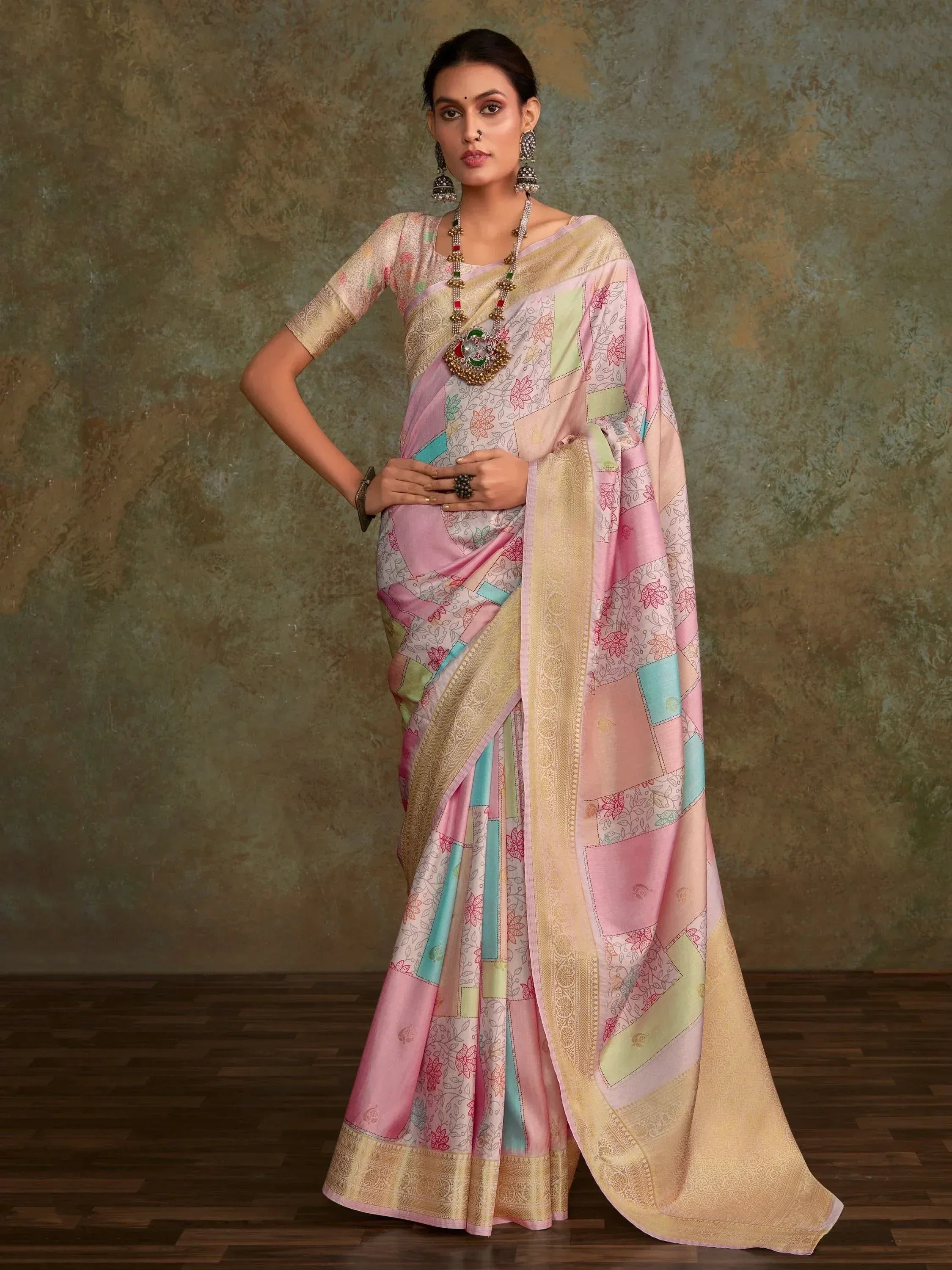 Woman in pastel patchwork saree with floral print and gold border, styled with traditional jewelry